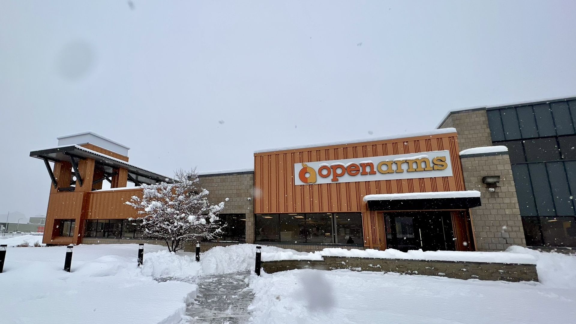 A photo of an orange building with a logo reading "Open Arms"