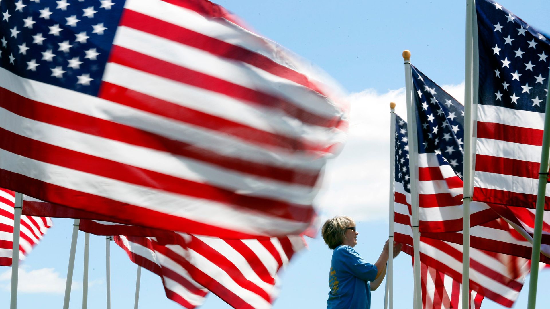A woman adjusts a flag in a display of several