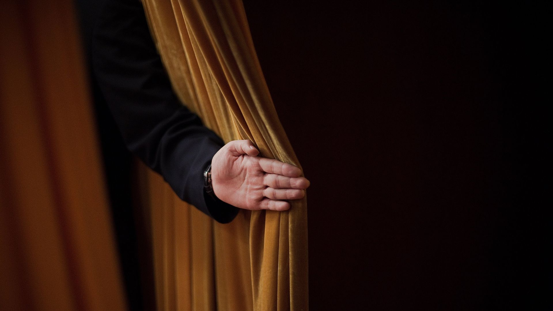 Arm of security guard holding back a curtain at the Party Congress.