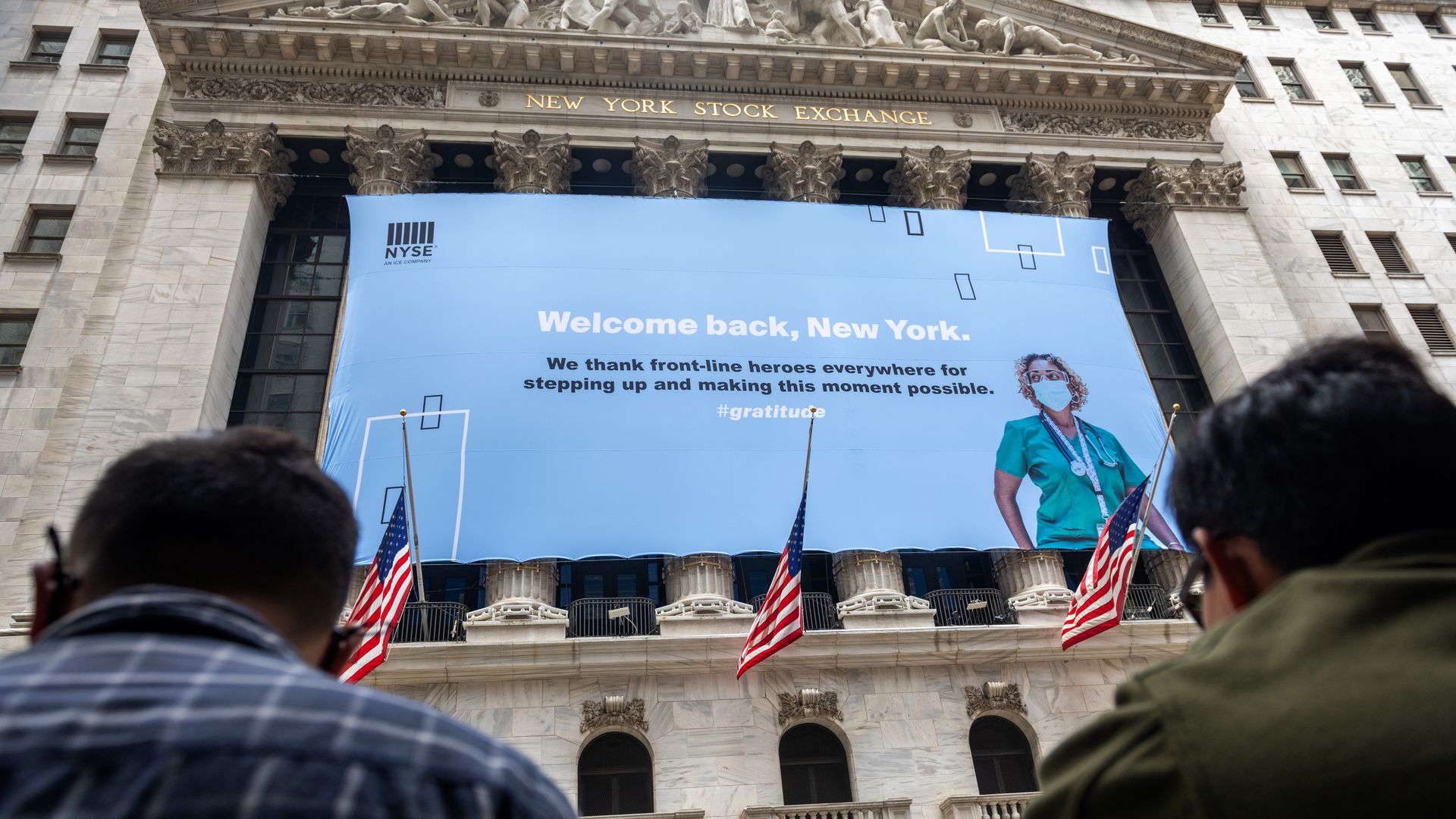A "Welcome Back, New York, we thank front-line heroes everywhere for stepping up and making this moment possible" banner hangs outside the New York Stock Exchange