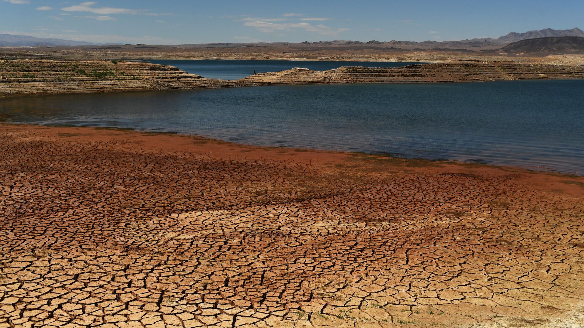 A man walks on a finger of exposed land at Lake Mead reservoir during the drought on July 9, 2022 in Boulder City, Nevada. 