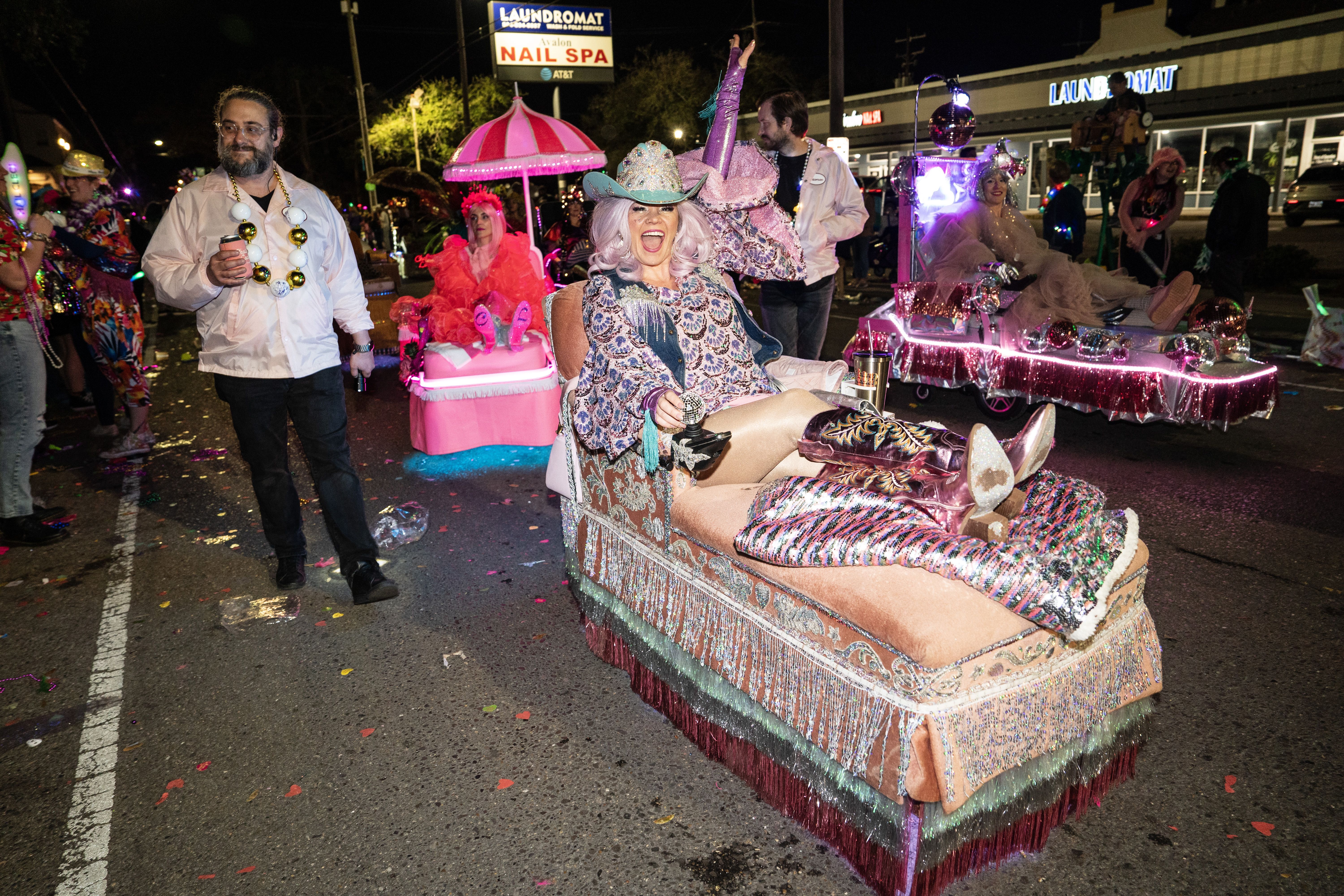 Women on decorated chaise lounges parade down the route.
