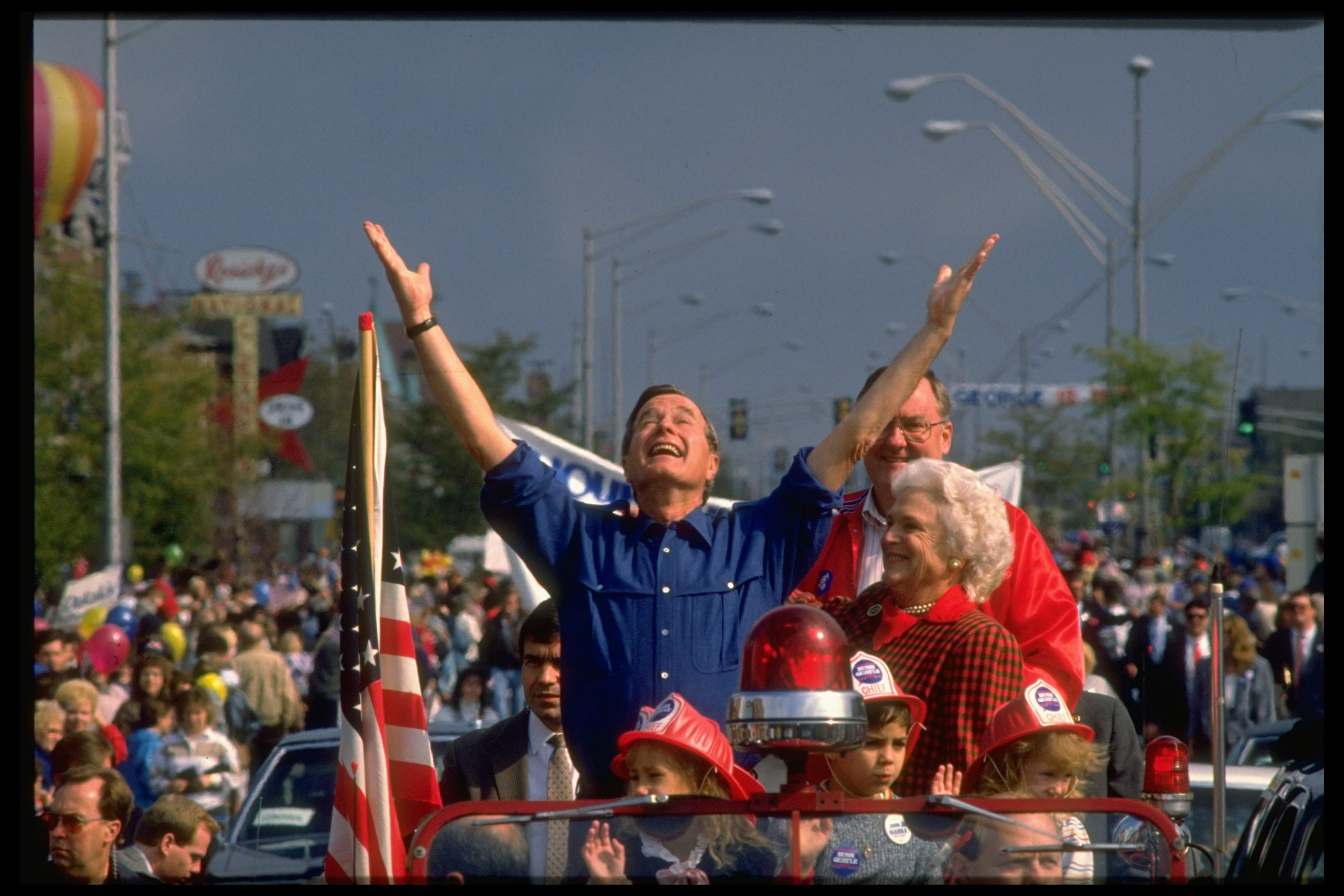 Photo of a man raising his hands during a parade.