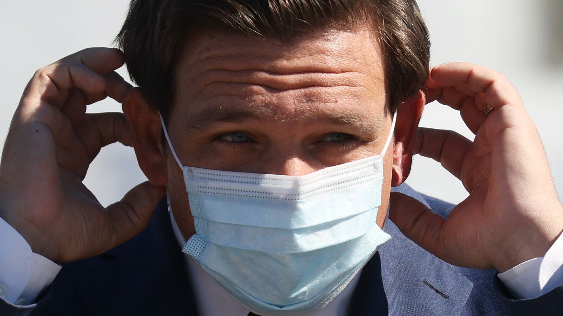 Picture of Florida Gov. Ron DeSantis putting on a mask