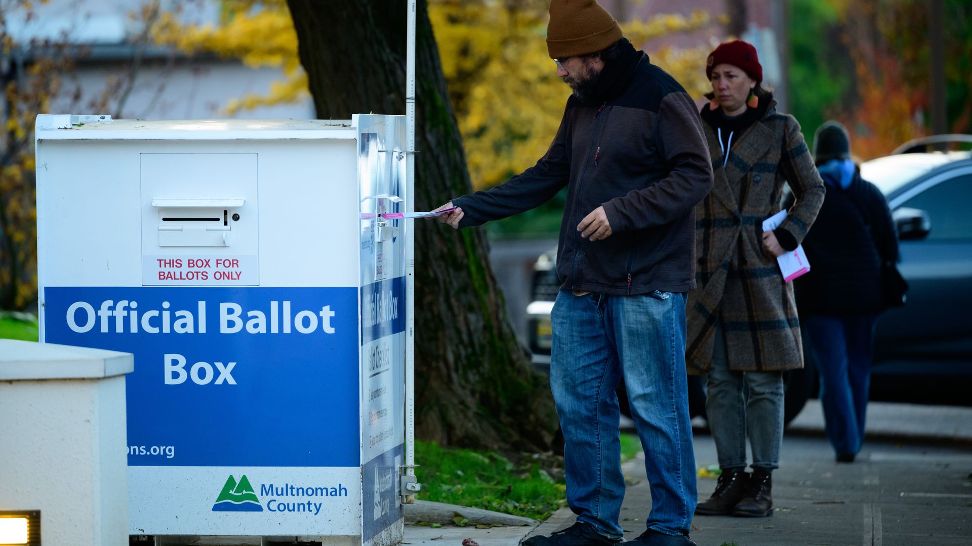 A person deposits a ballot into an official ballot drop box.