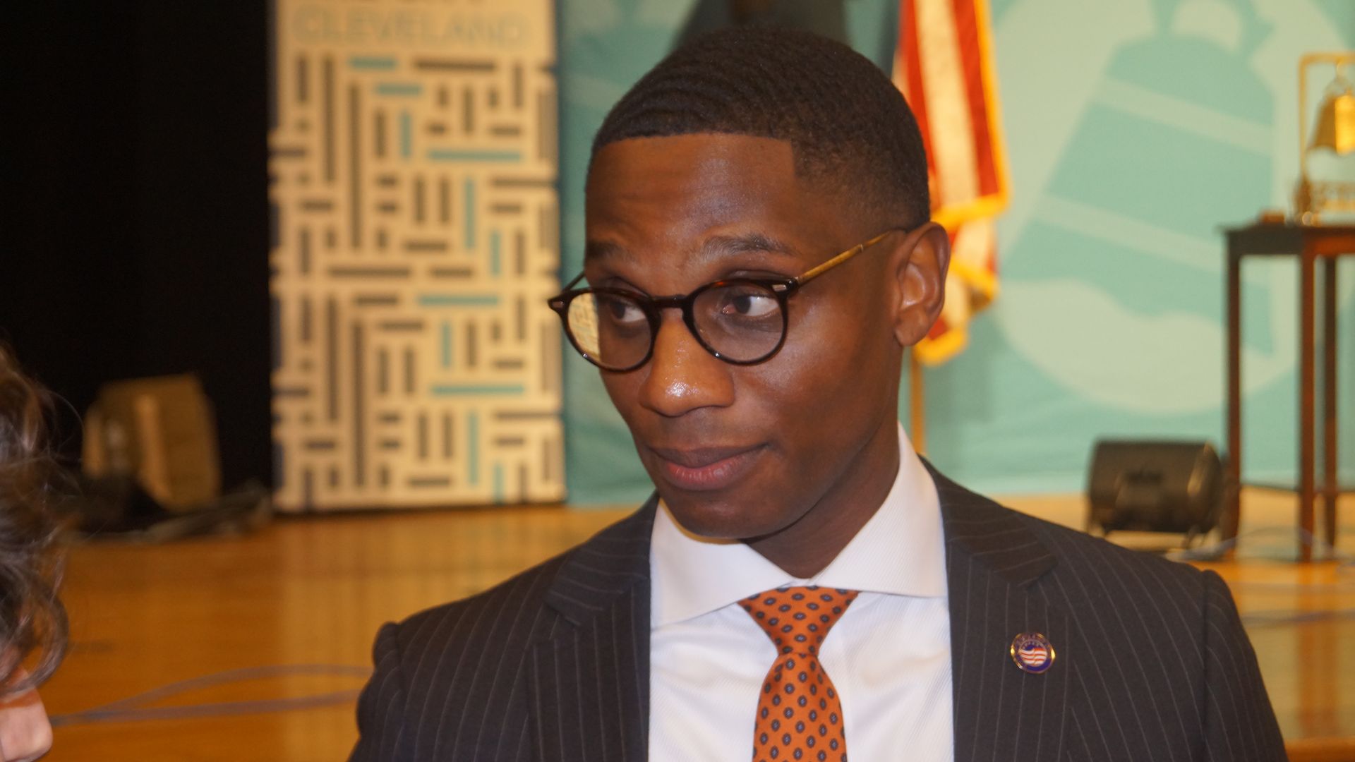 Mayor Justin Bibb in a suit, speaking to reporters