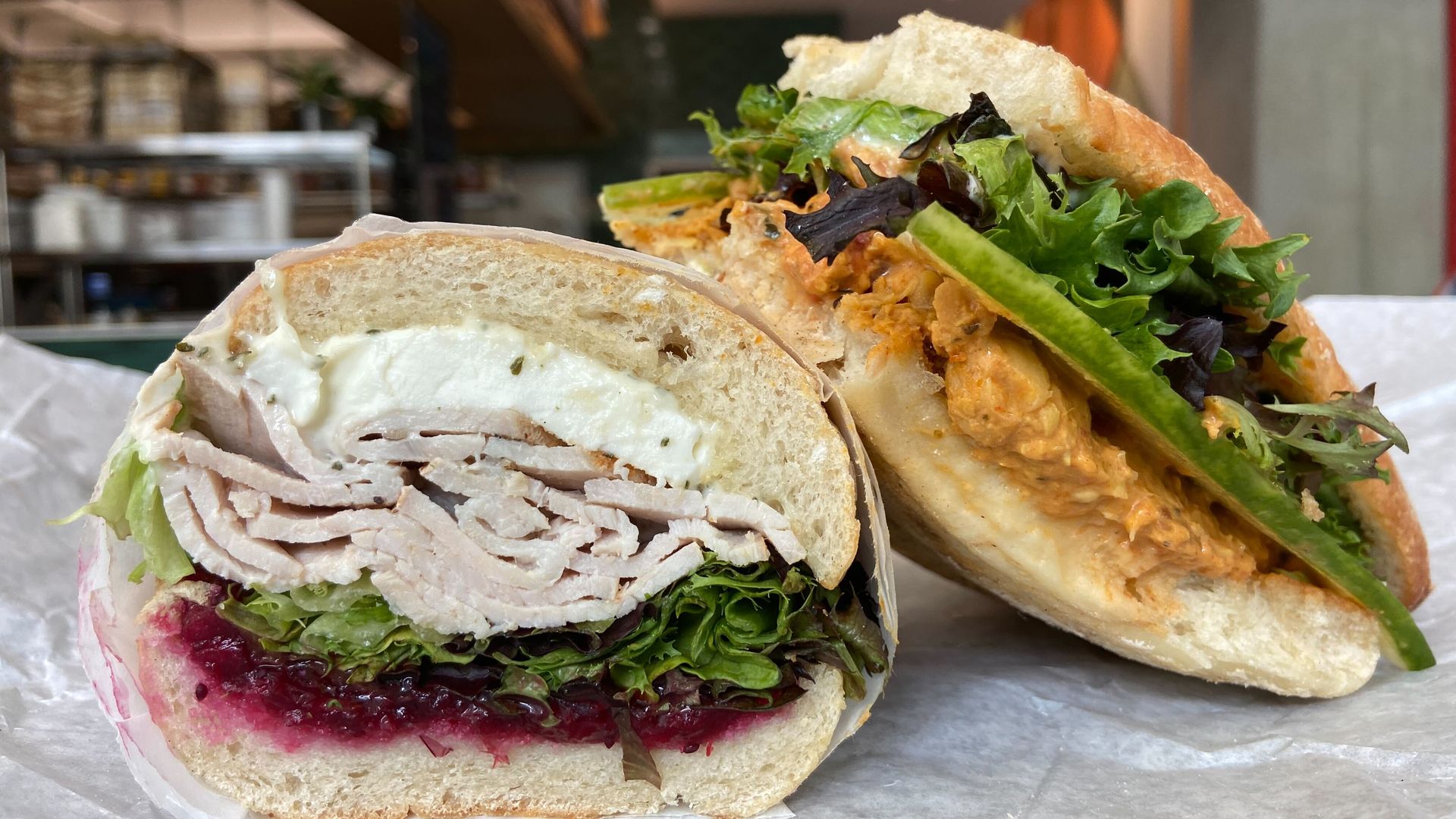 A turkey sandwich with cranberry relish and mozzarella and a tika masala sandwich, both on ciabatta bread