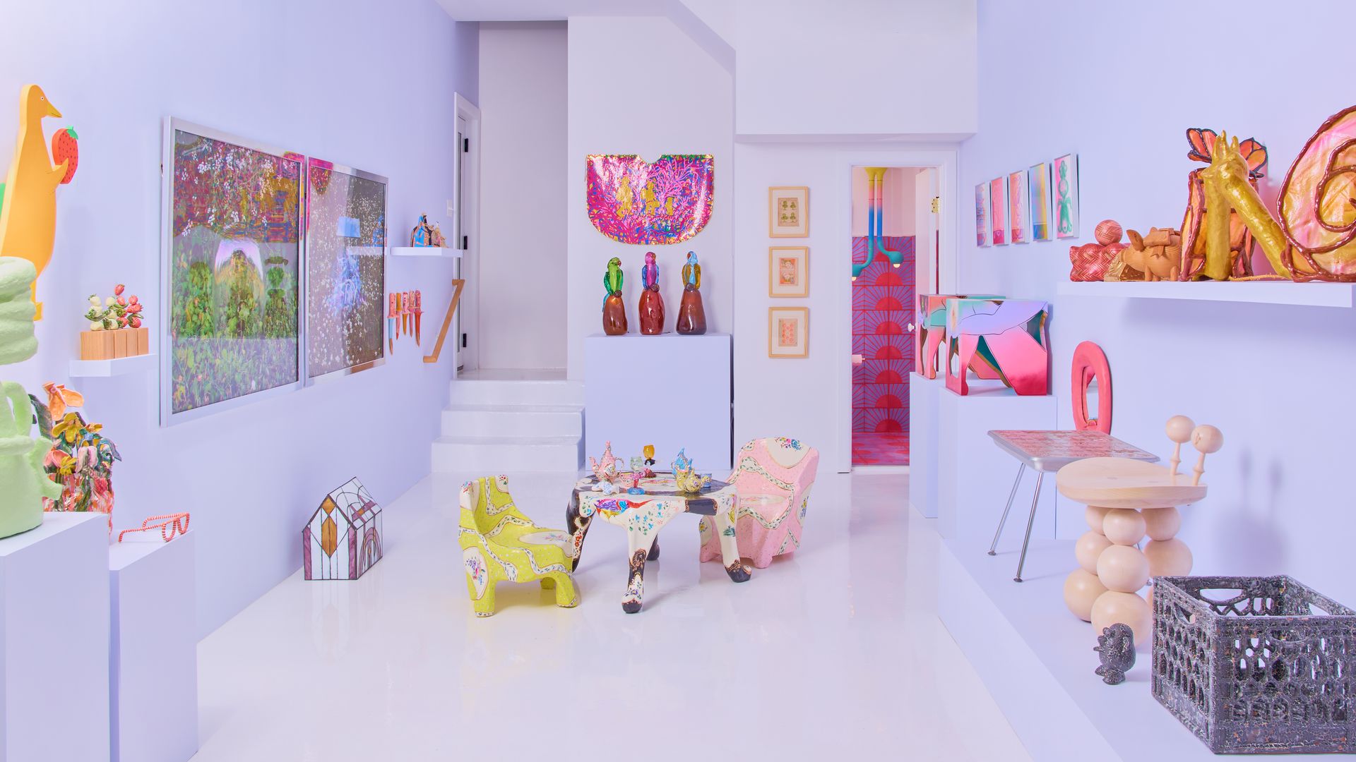 A photo showing the interior of an art gallery filled with colorful, child-like pieces of art.
