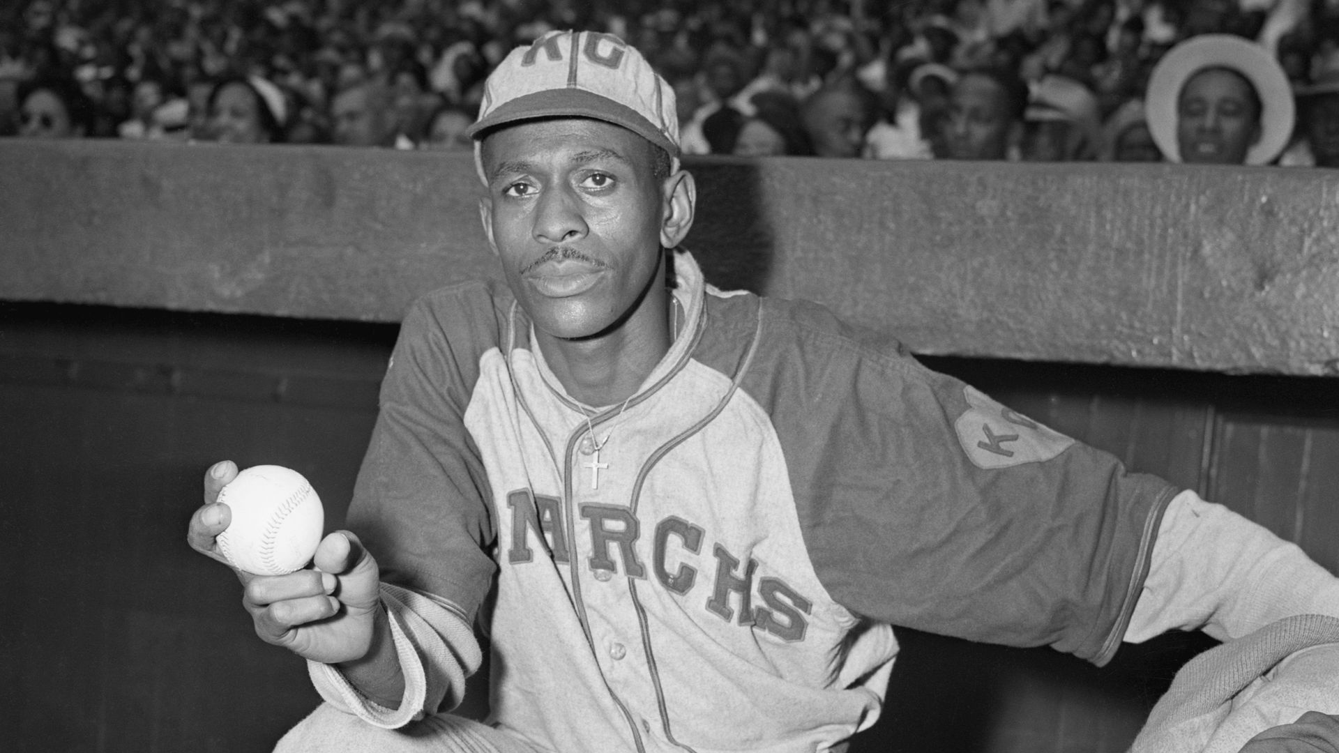 Satchel Paige, pitcher for the Negro League's Kansas City Monarchs, stands at the top of the dugout with baseball in hand in 1942.
