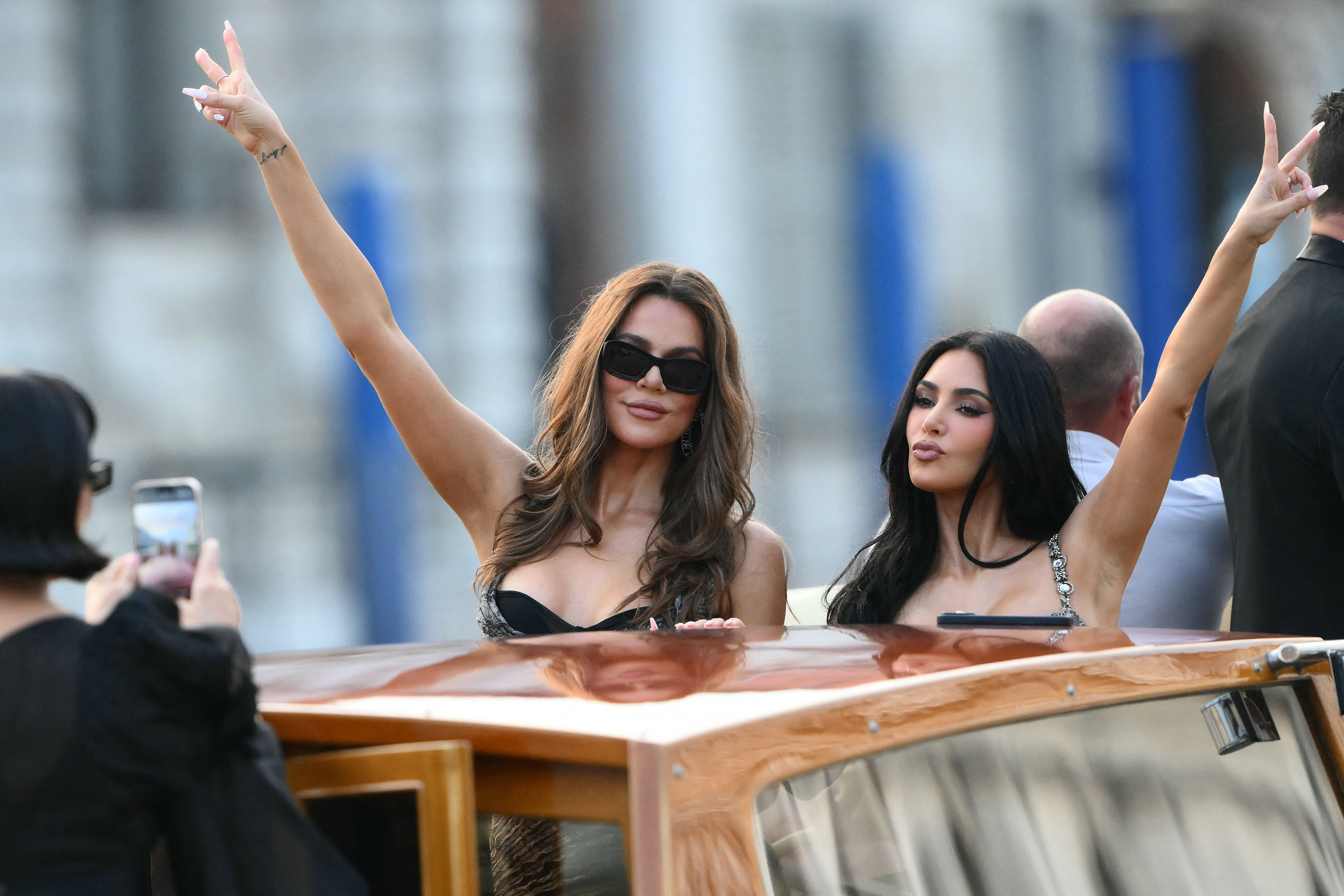 US television personality Kris Jenner takes pictures of US Khloe Kardashian (C) and US reality TV personality Kim Kardashian on a taxi boat as they leave the Gritti Palace Hotel ahead of the wedding of Amazon's founder Jeff Bezos with Lauren Sanchez in Venice on June 26, 2026. Celebrities in superya