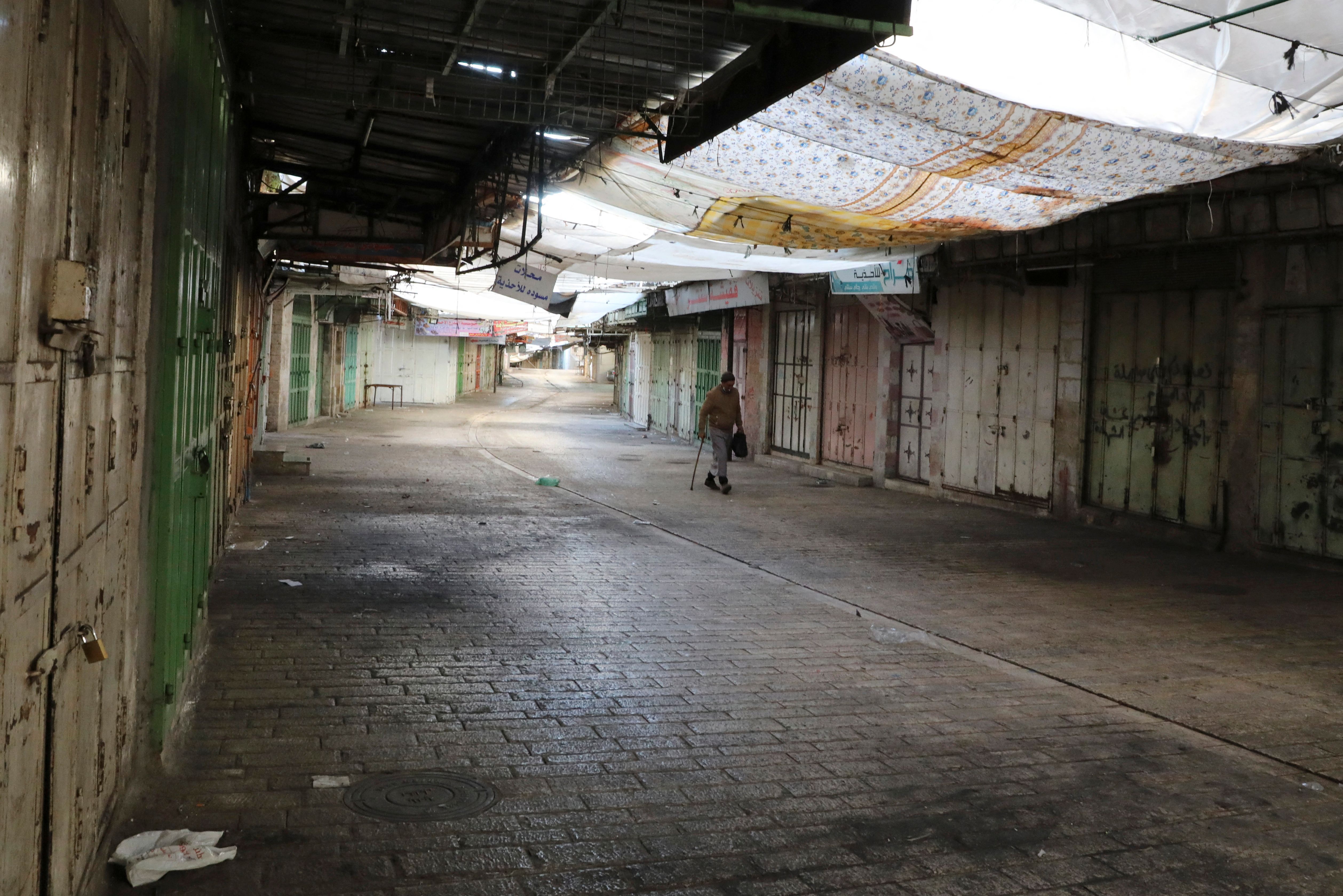 A man walks past shuttered Palestinian stores in Hebron during Tuesday's strike. 