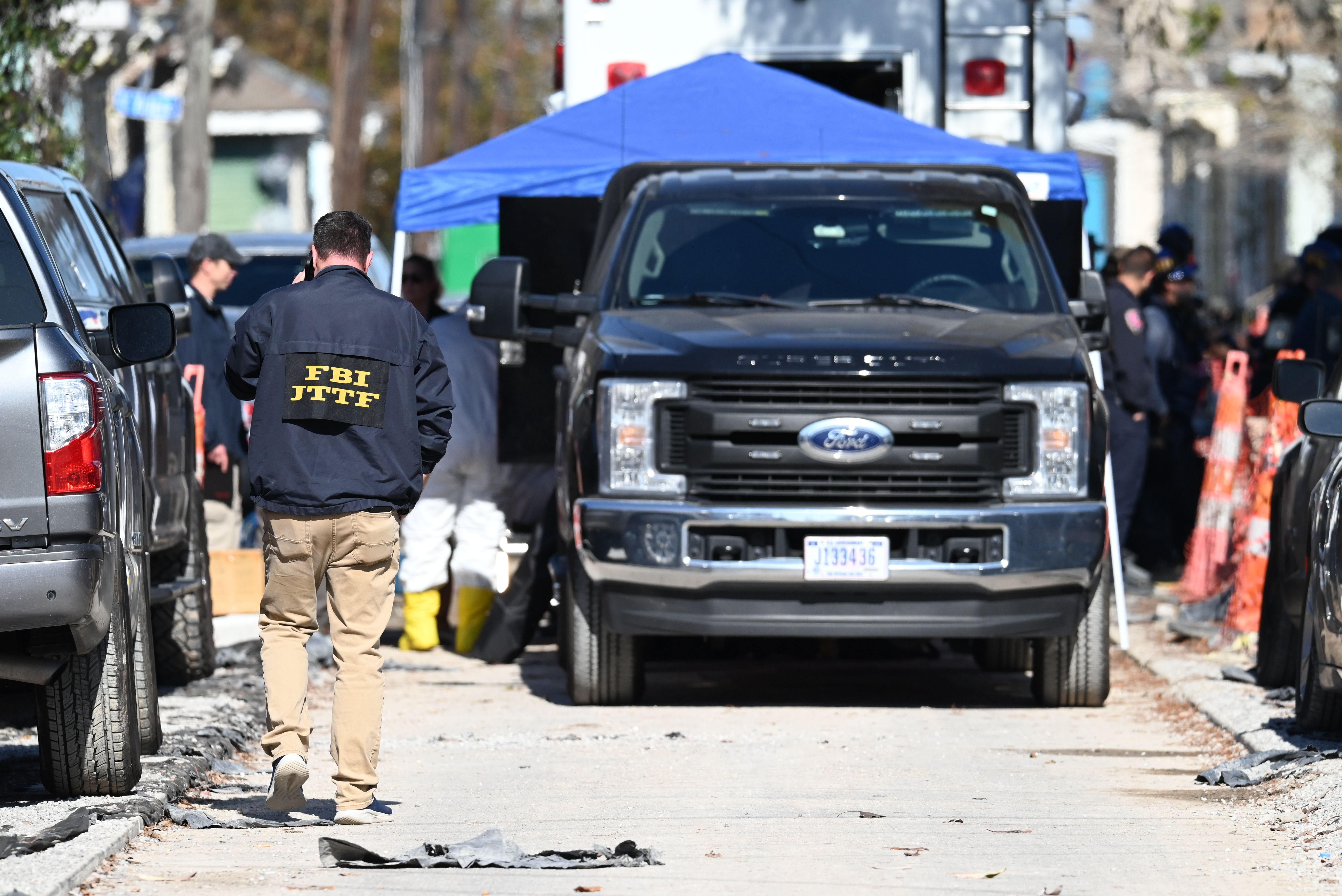 A tent covers a truck, parked in the middle of New Orleans neighborhood street.