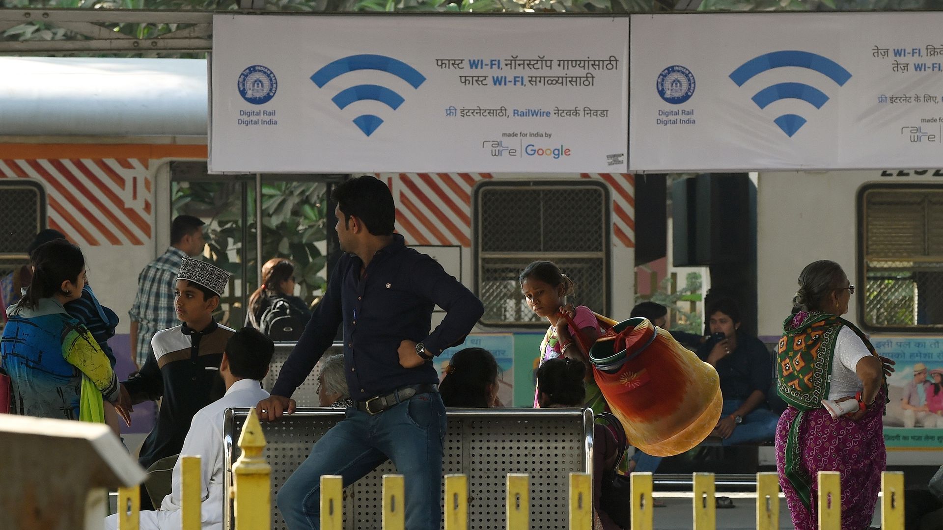 A group of people beneath signs advertising Google's wifi hotspots in India