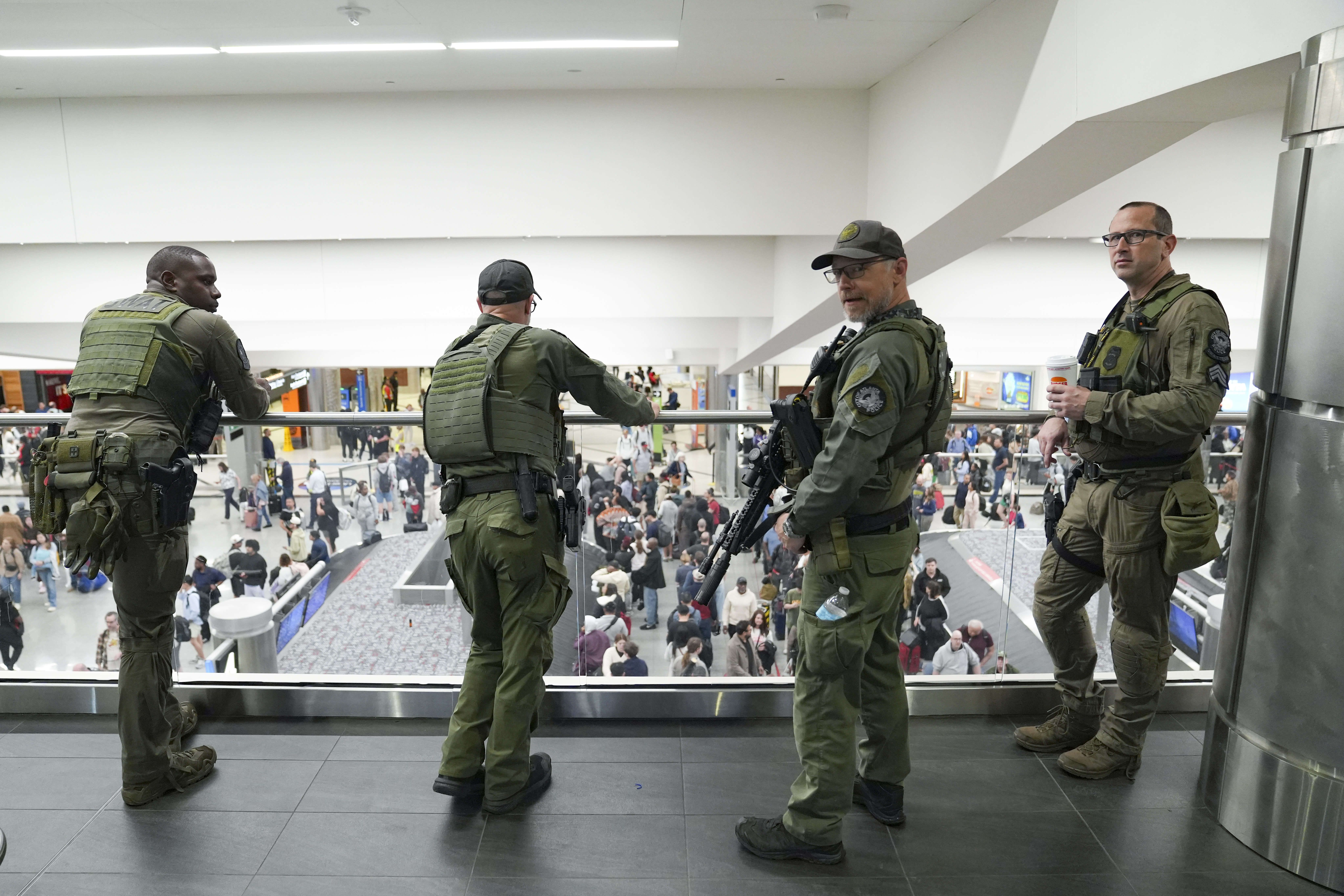 Officers look on as travelers stand in long lines at Atlanta Hartsfield-Jackson International Airport yesterday. Photo: Megan Varner/Getty Images