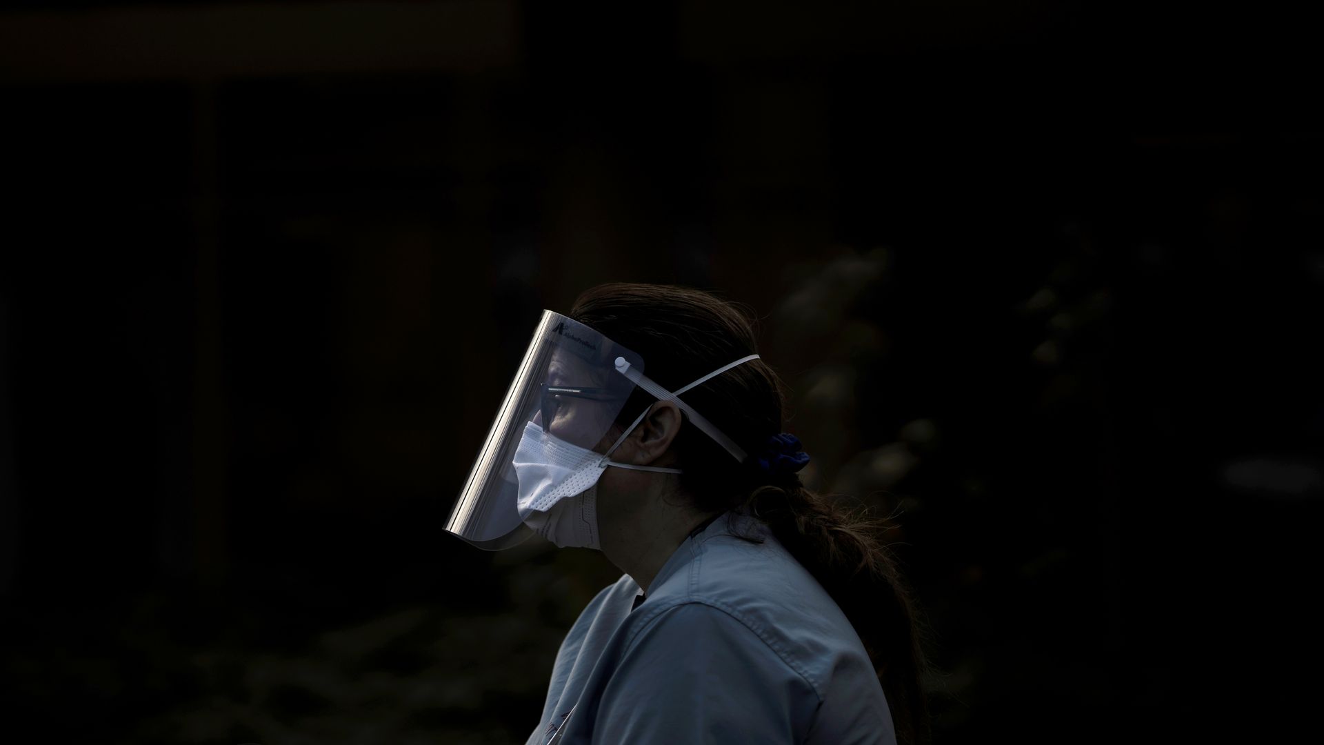 Photo of a health care worker wearing a mask and face shield in scrubs