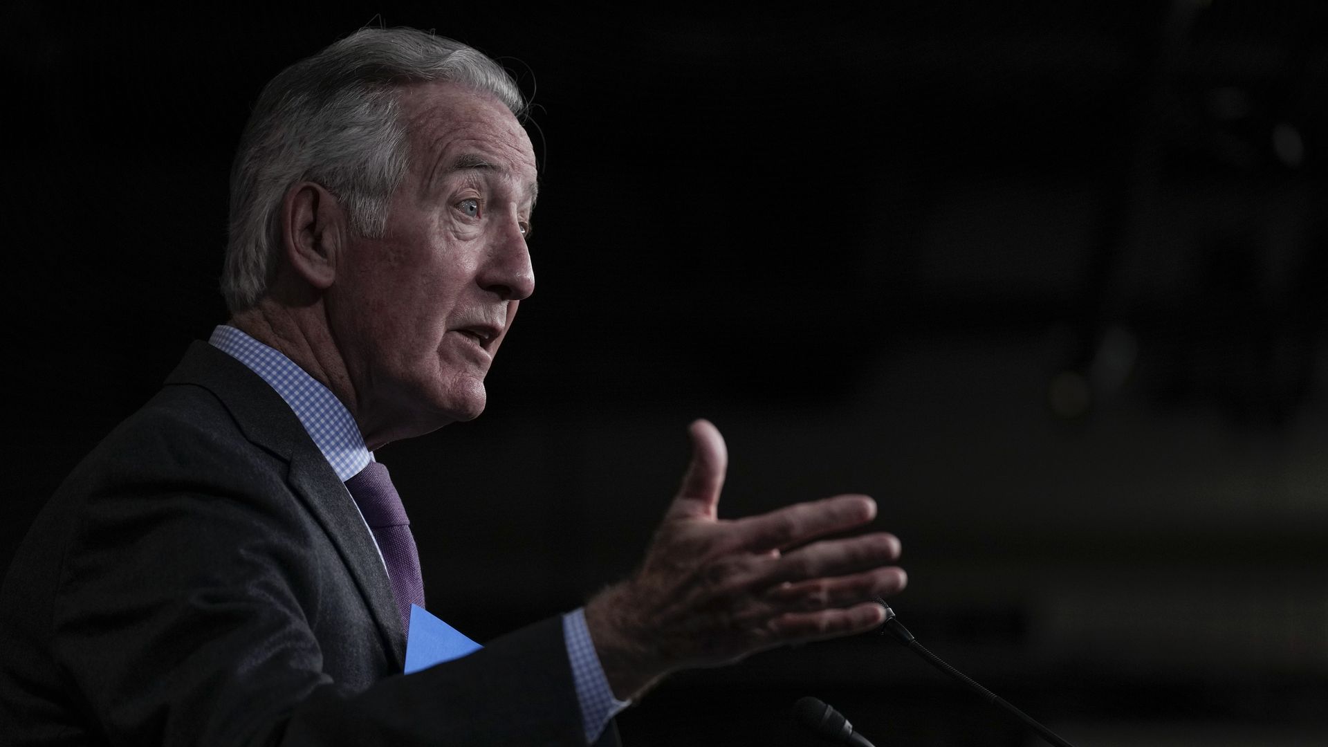 Rep. Ritchie Neal, wearing a gray suit and holding up his hand against a black backdrop.