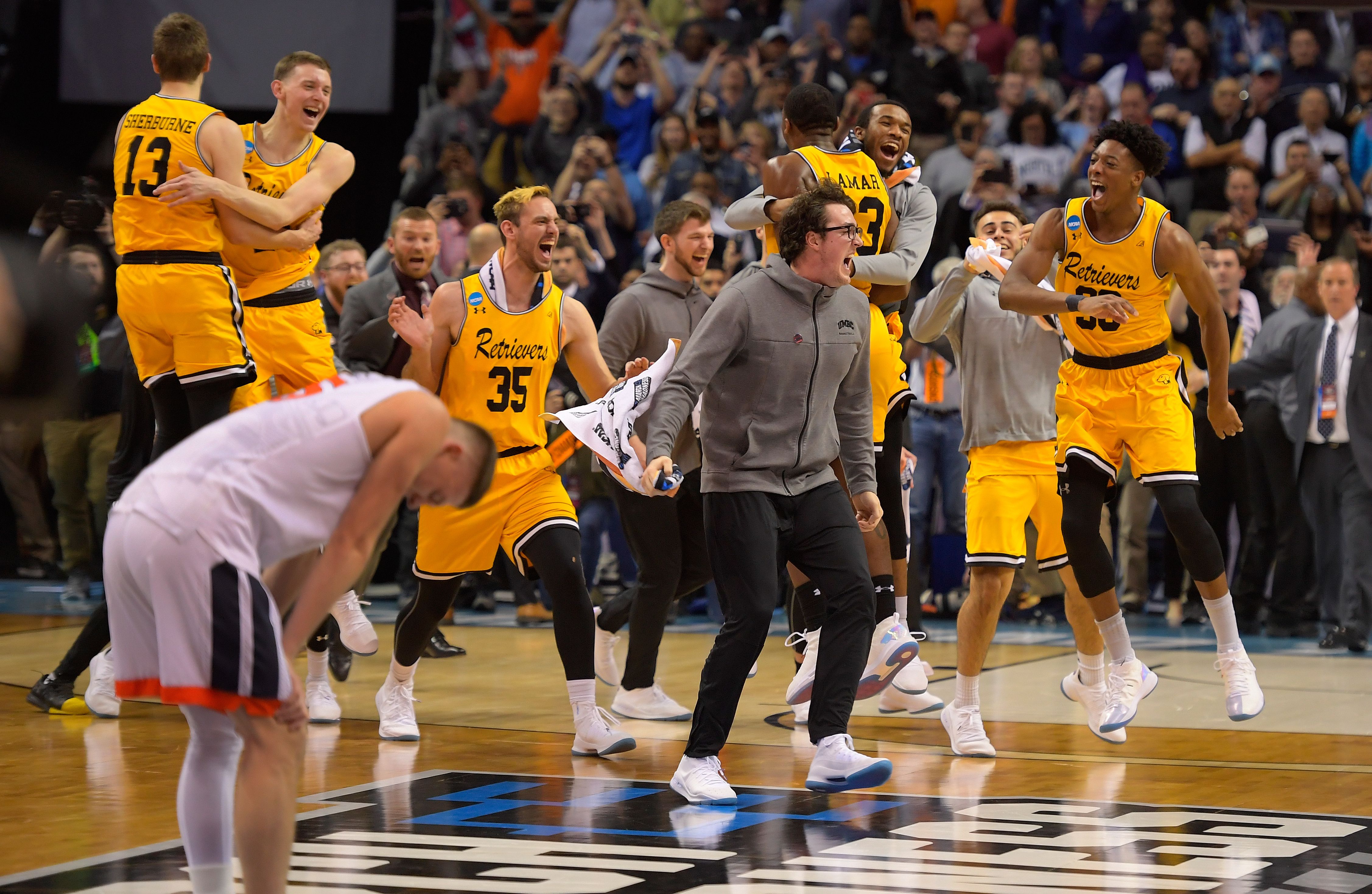 UMBC basketball players celebrate while a Virginia player stands in disappointment. 