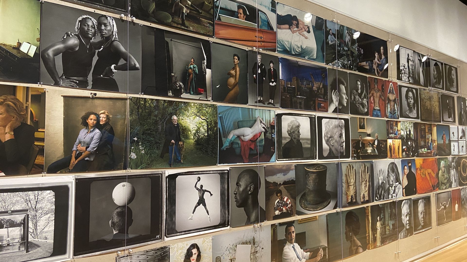 Gallery wall featuring a diverse mix of photographs including portraits, artistic nude studies, historical figures, and candid scenes, arranged in multiple rows with vivid colors and black-and-white images.