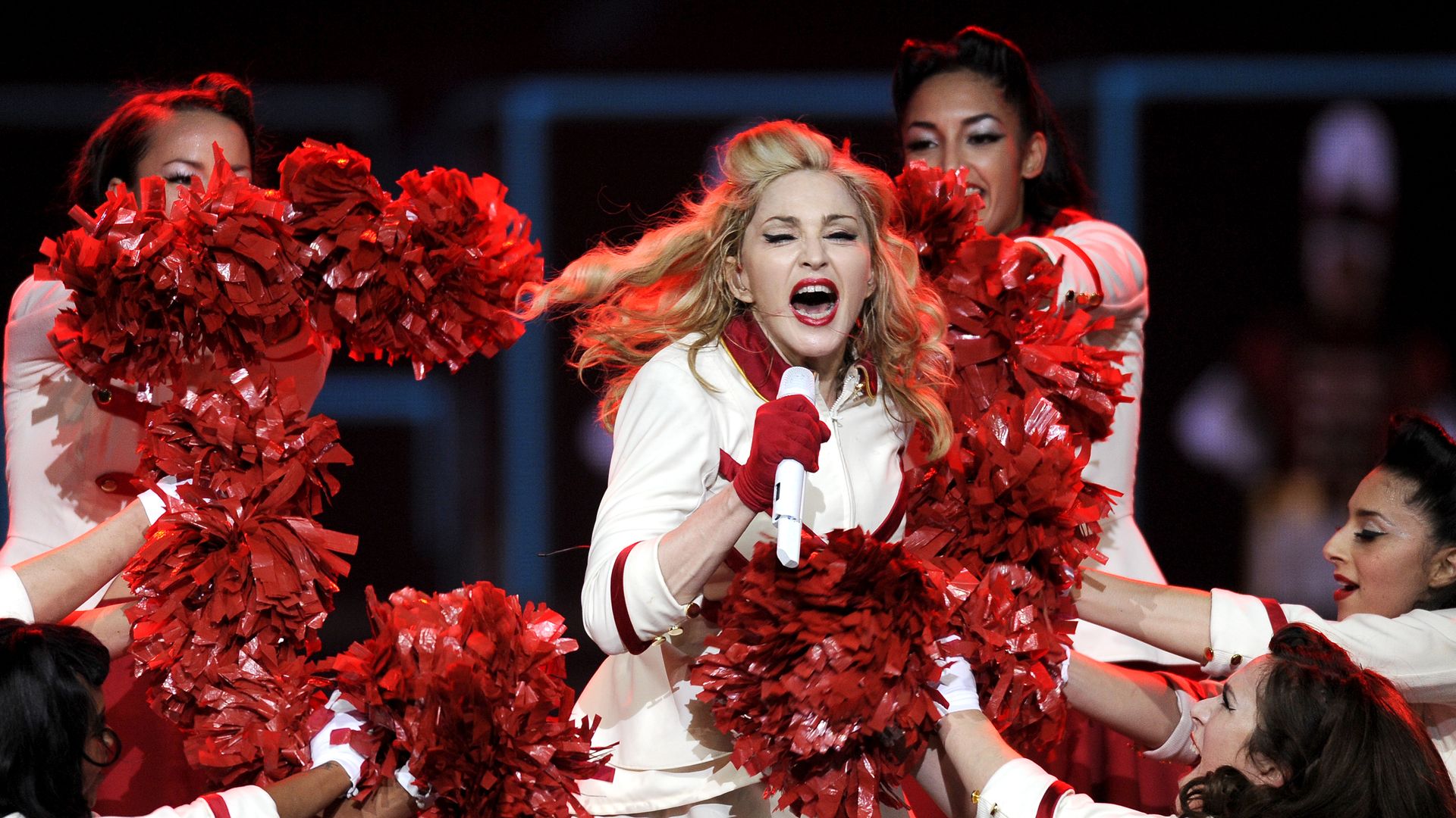 Singer Madonna, in a red and white cheerleader uniform, sings in Houston