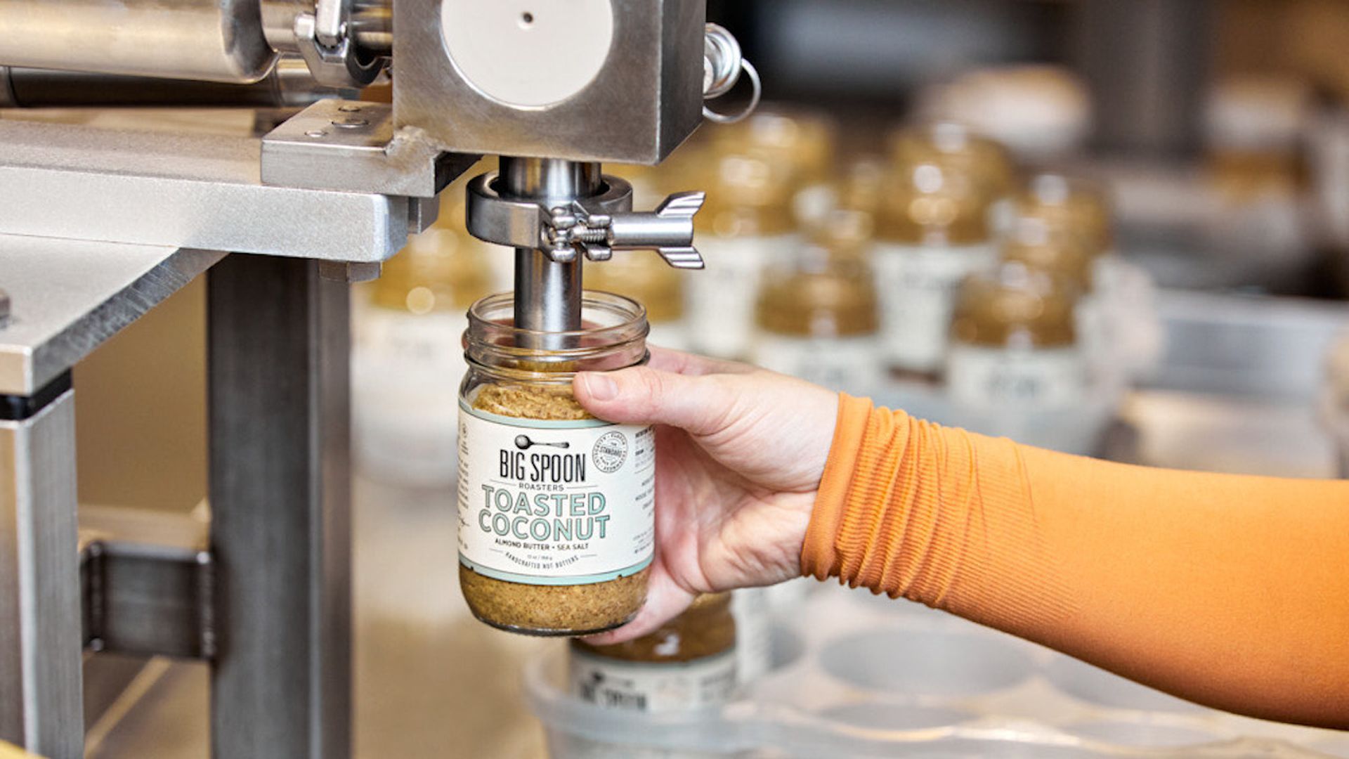 A worker makes nut butter with a machine. 