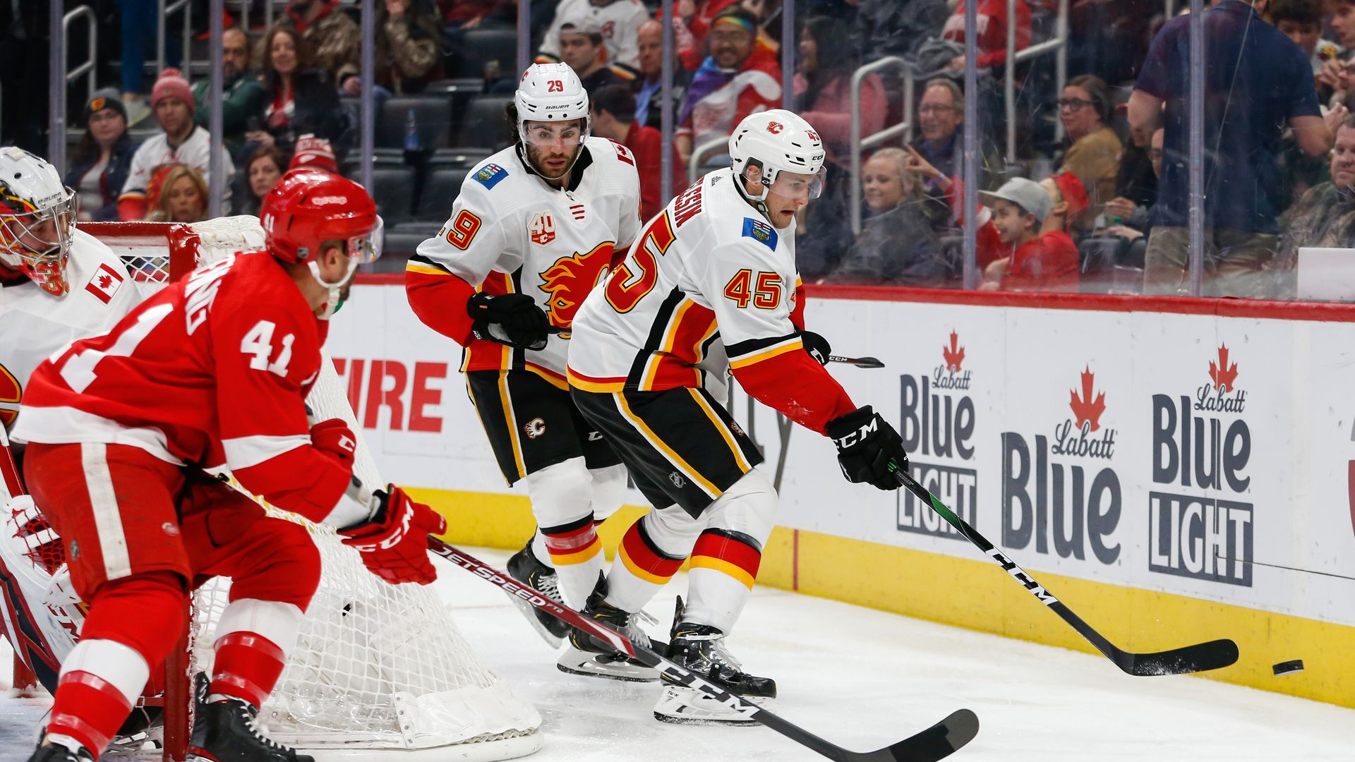 Photo of hockey players chasing a puck in a crowded stadium