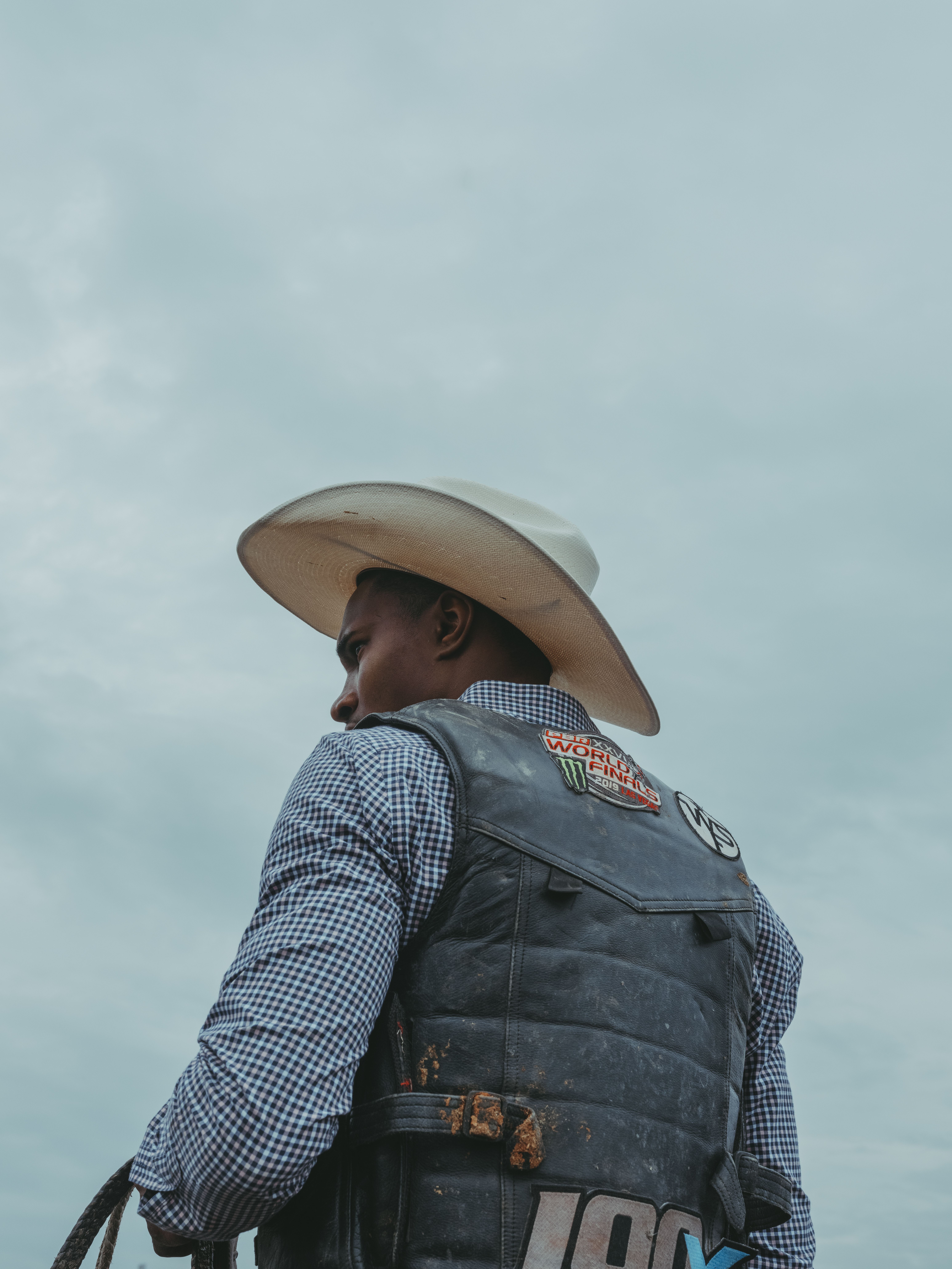 Photo of a Black cowboy wearing a cowboy hat and bull-riding safety vest.