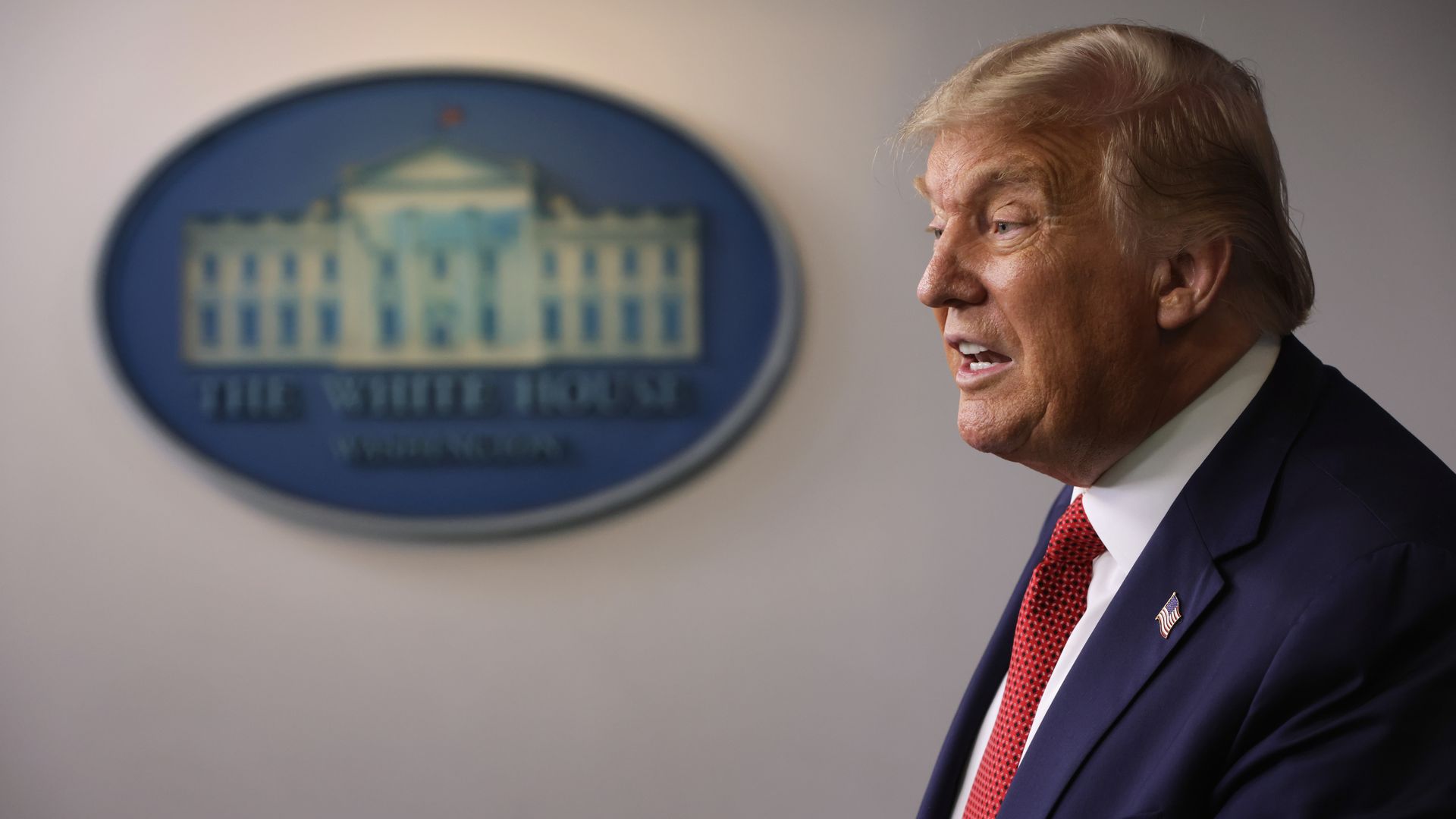 Trump in front of the White House logo 