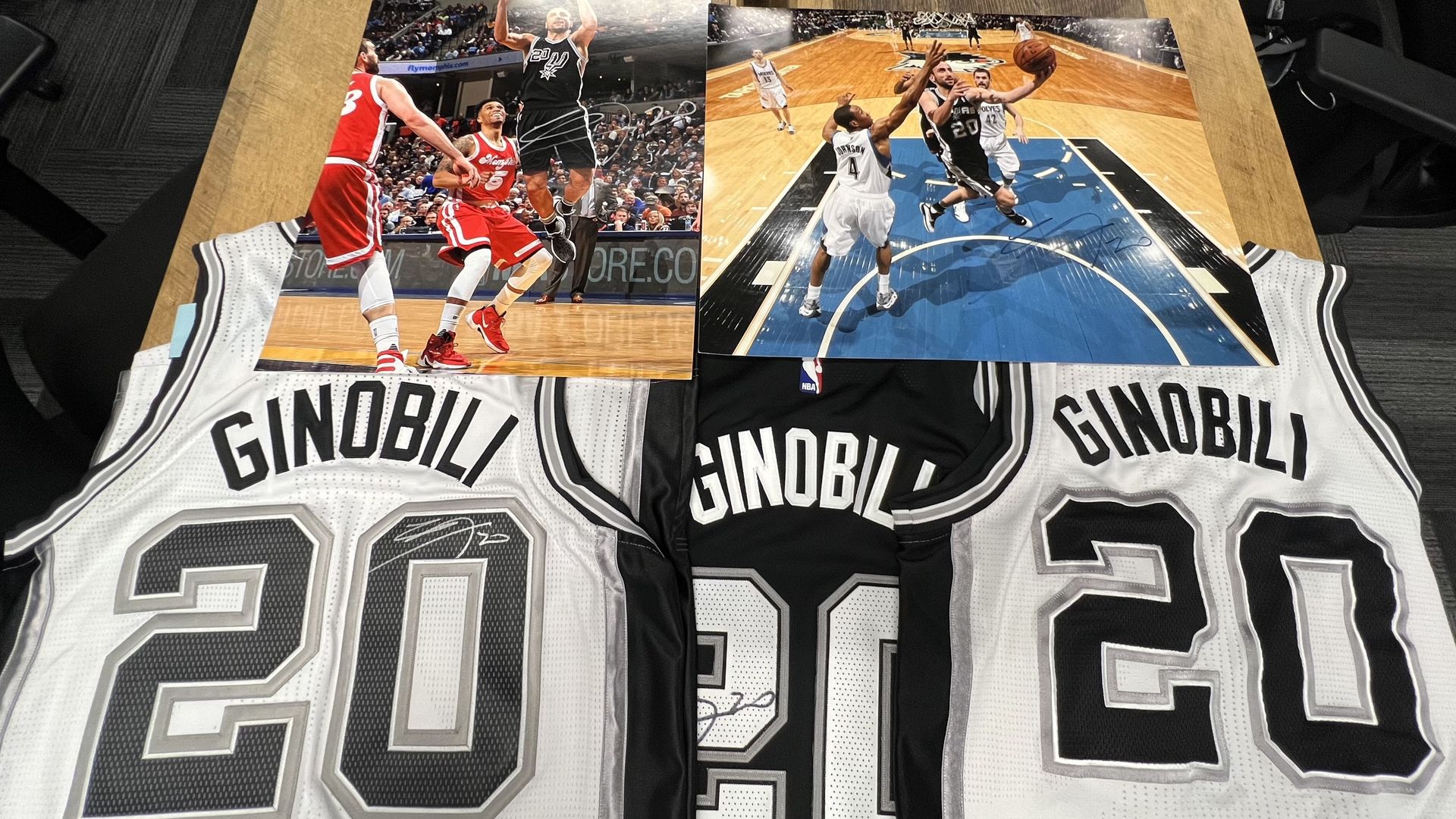 Manu Ginobili jerseys and prints displayed on a table. 