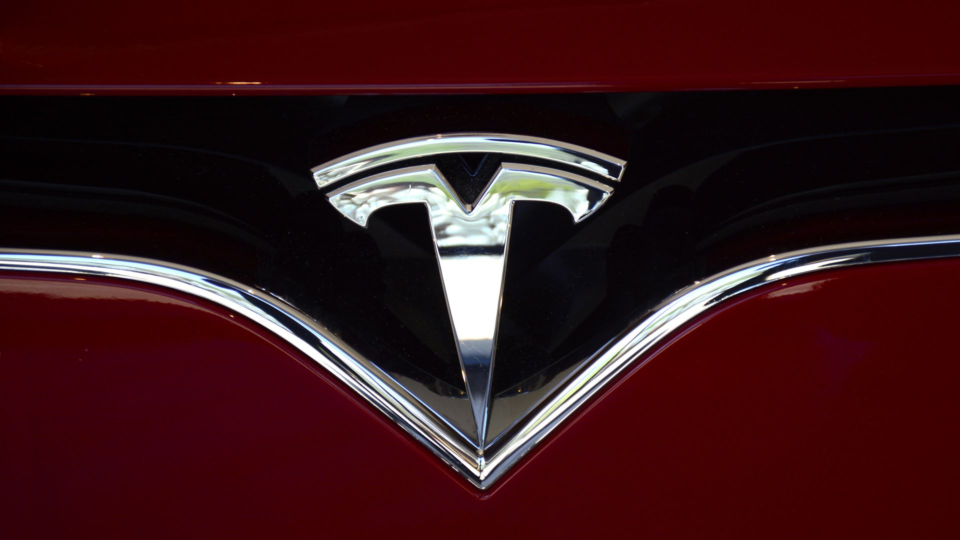 The Tesla brand logo embellishes the nose of a Tesla electric sedan 