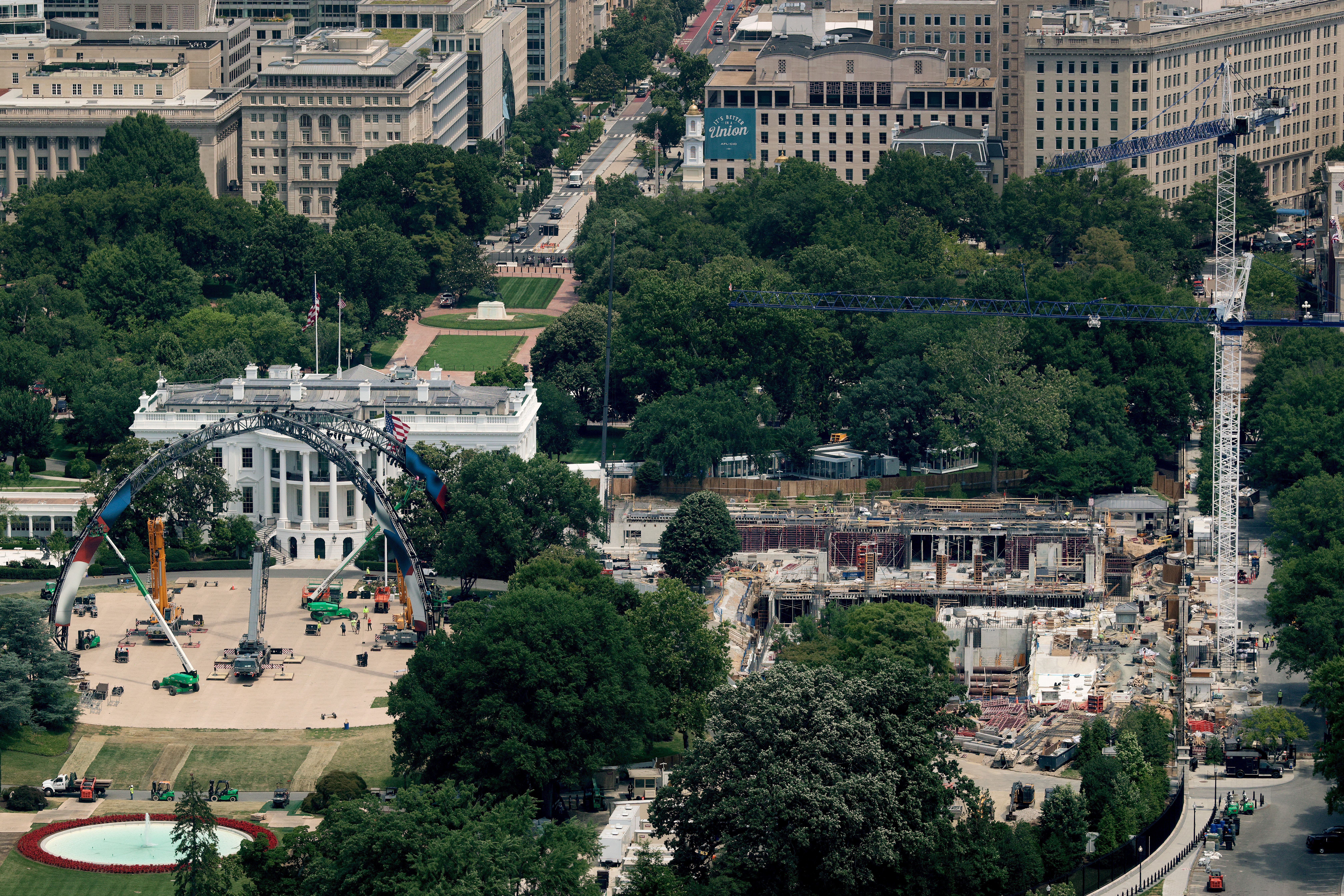 An aerial image showing the White House lawn's "Claw" — constructed for the UFC fight — being dismantled, while the construction zone with a crane continues to operate on the east wing of the White House.