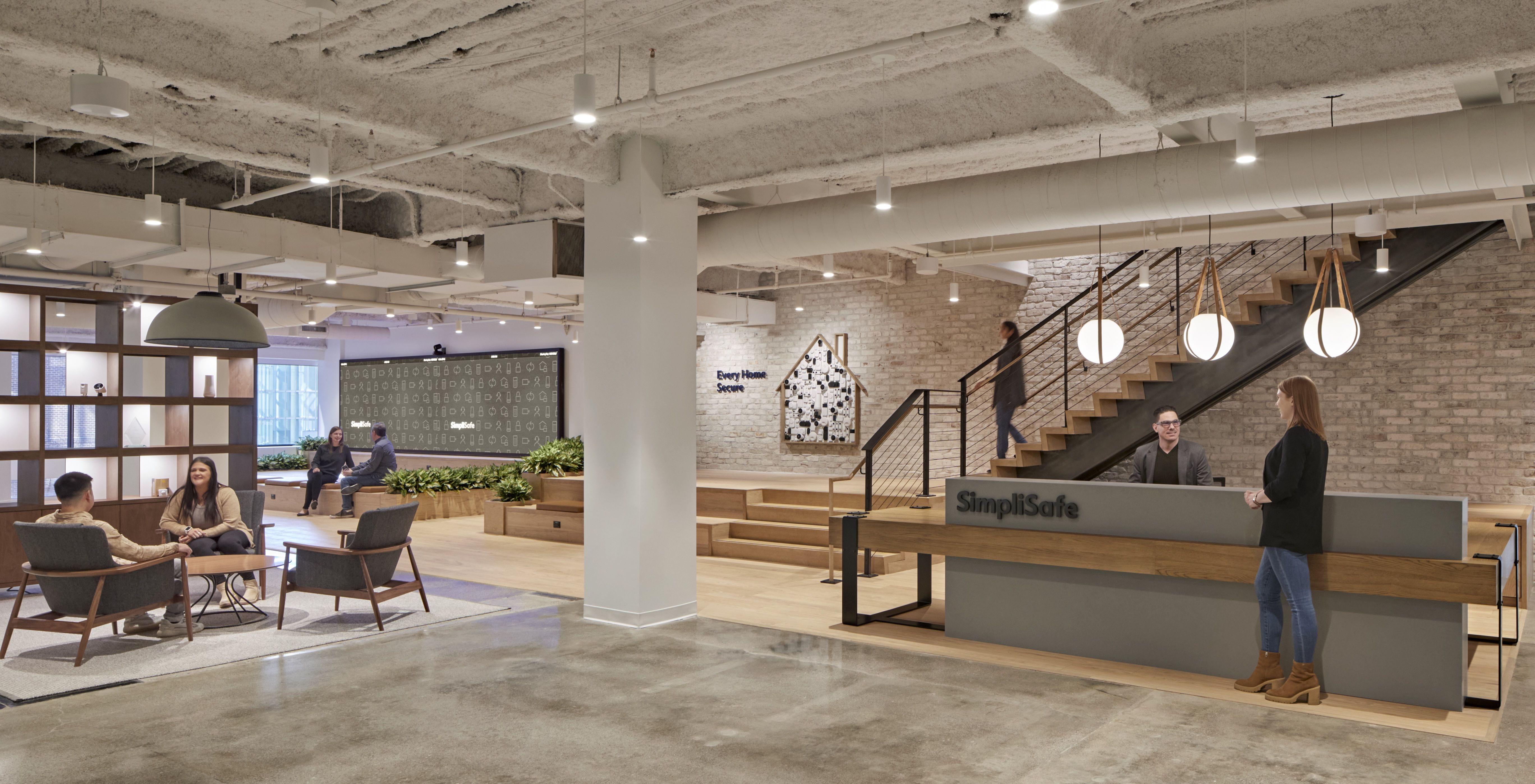 The entrance of SimpliSafe's Boston HQ, which shows in the background a receptionist's desk and lounge chairs.