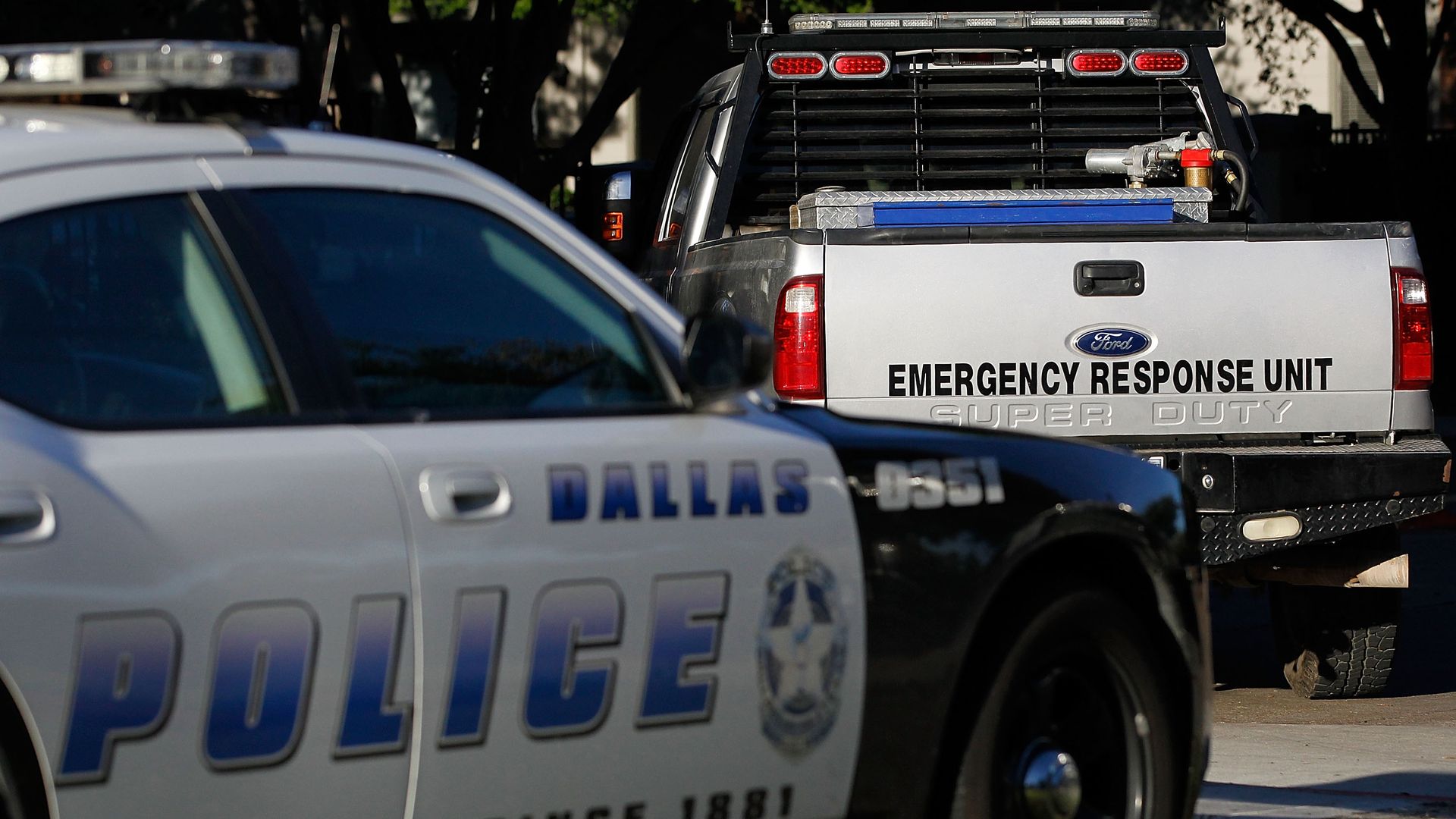 A truck with the words EMERGENCY RESPONSE UNIT is parked in front of a Dallas Police squad car.