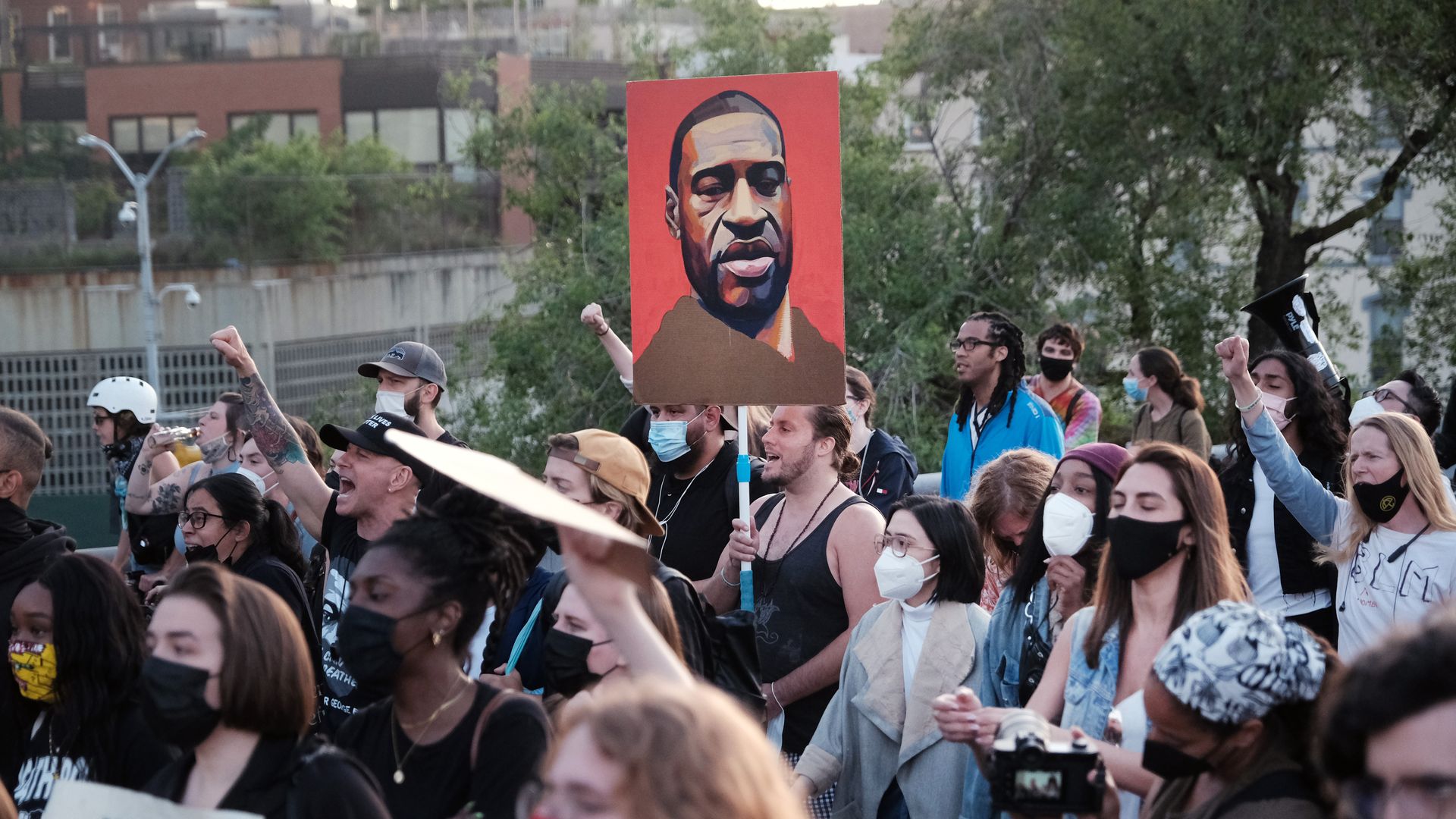 Photo of a crowd of protesters and a sign with a painting of George Floyd's profile