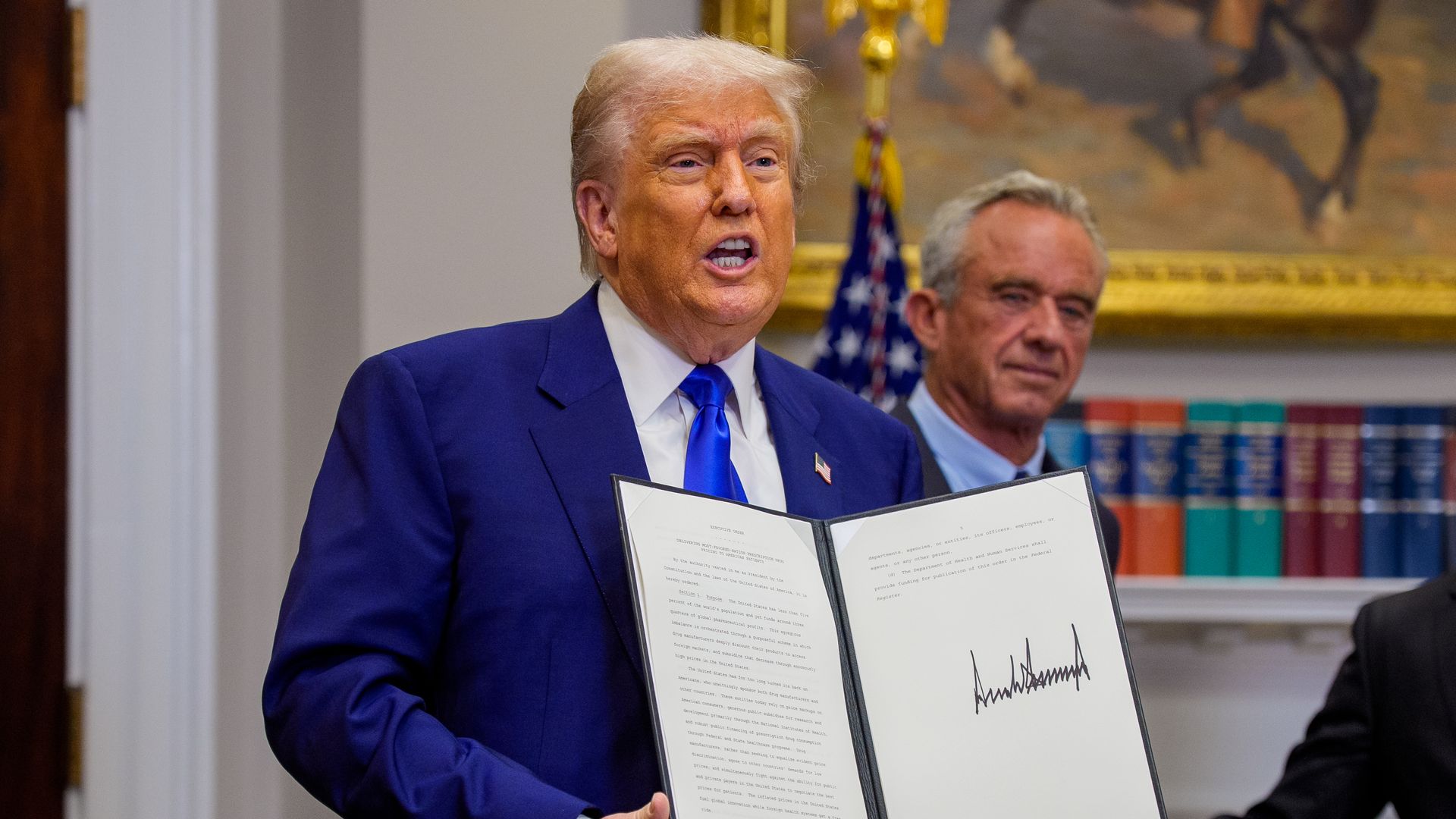 President Donald Trump, accompanied by Health and Human Services Secretary Robert F. Kennedy Jr. (R), holds up an executive order at the White House on May 12, 2025, in Washington aimed at cutting pharmaceutical prices.