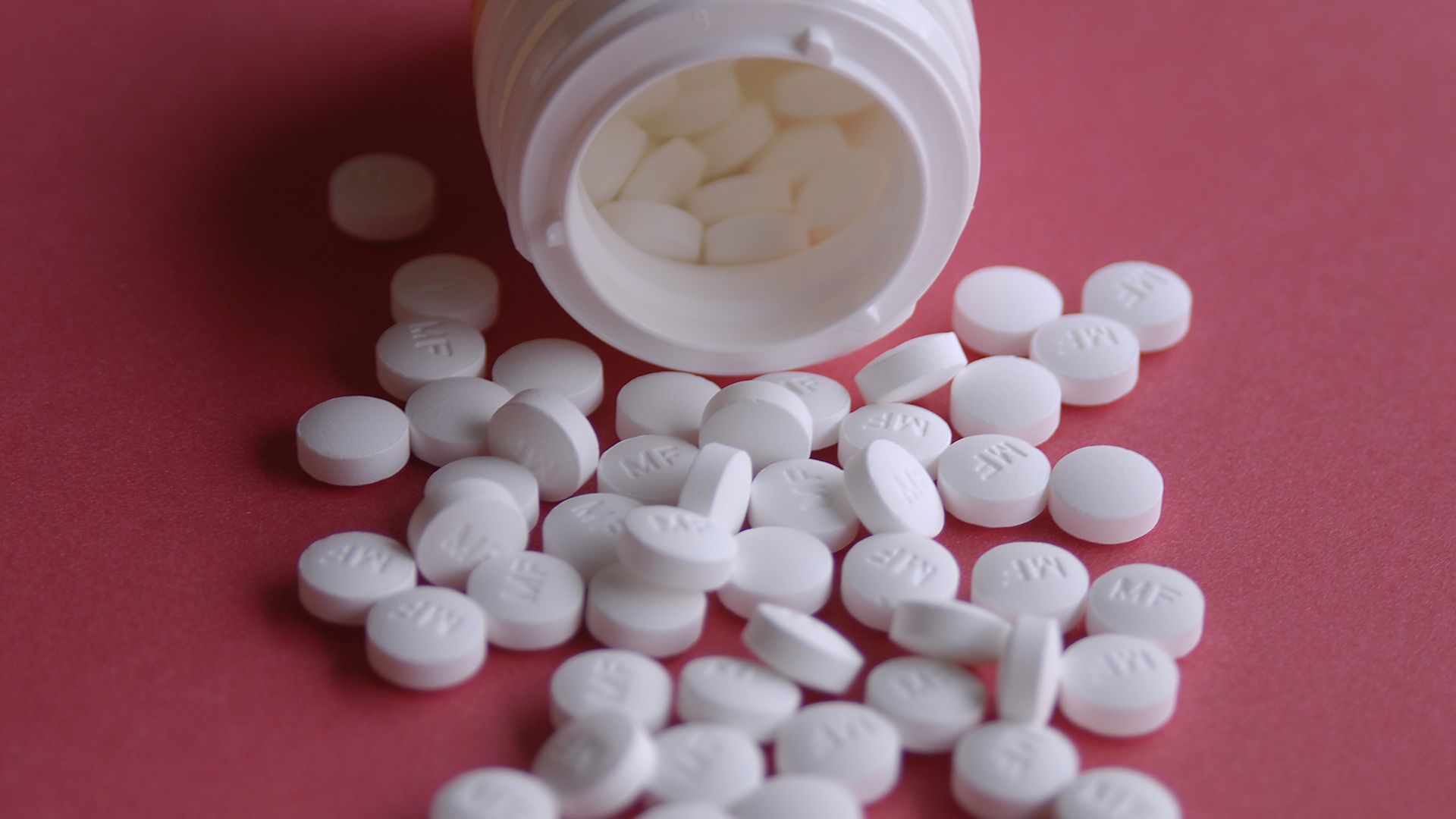 A bottle with white pills around it.