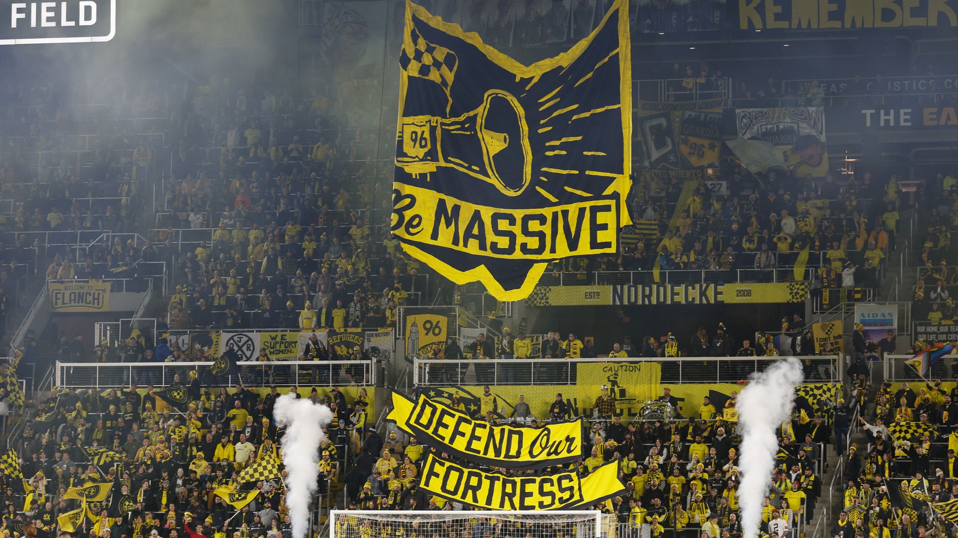 A photo of the Nordecke Columbus Crew fans with a banner in the shape of Ohio that says "Be massive"