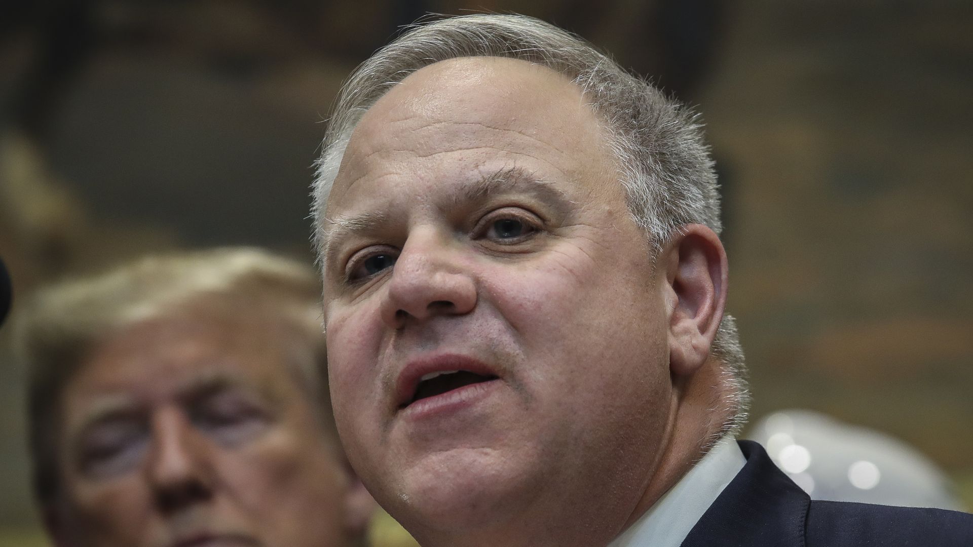 In this image, David Bernhardt stands in front of President Trump