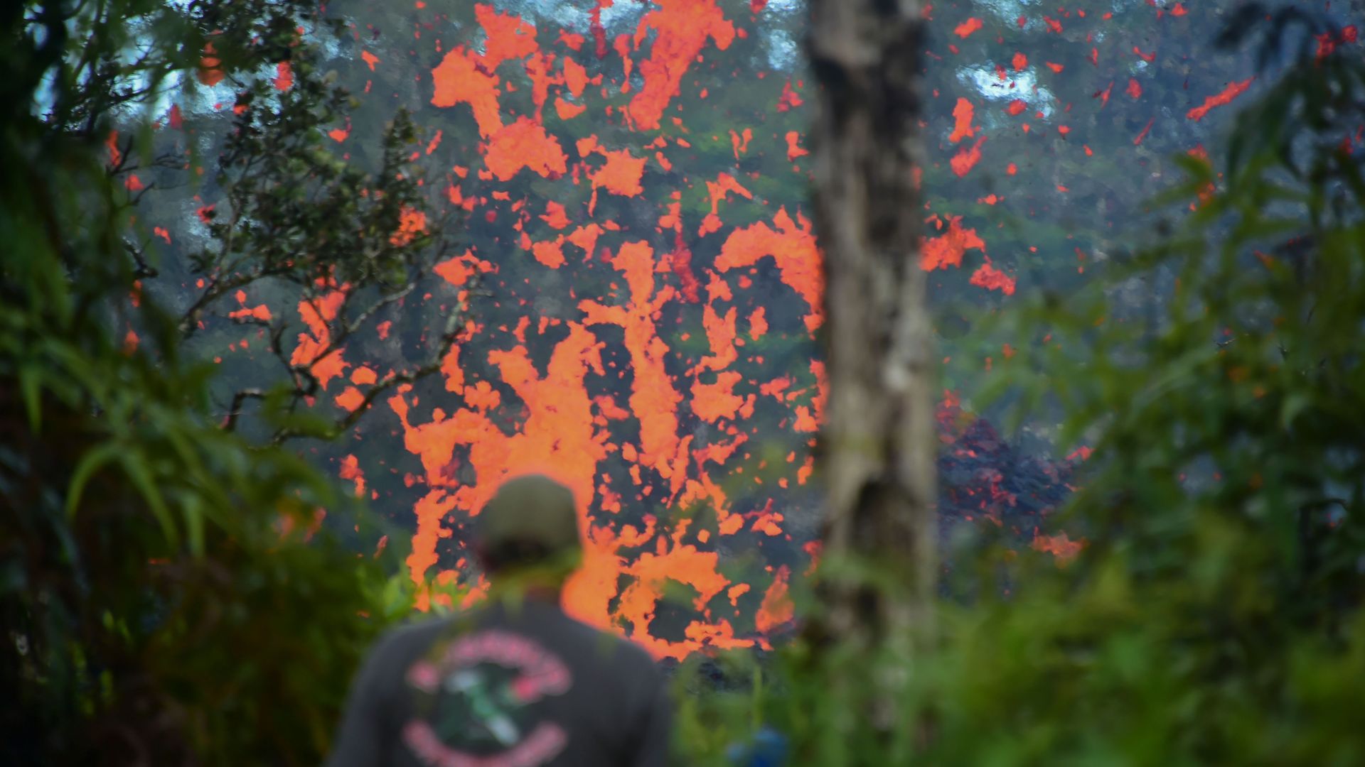 A man watches as lava is seen coming from a fissure