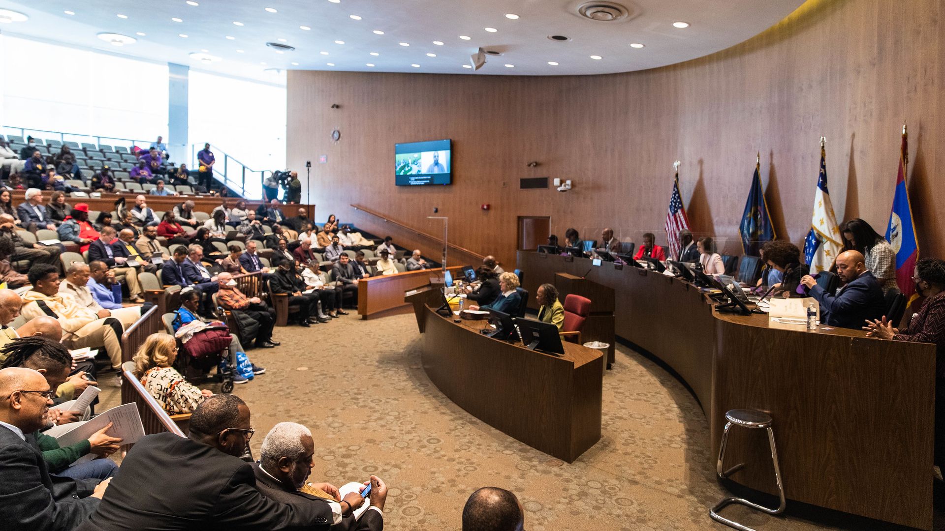 City Council's chambers. The members face a packed audience.
