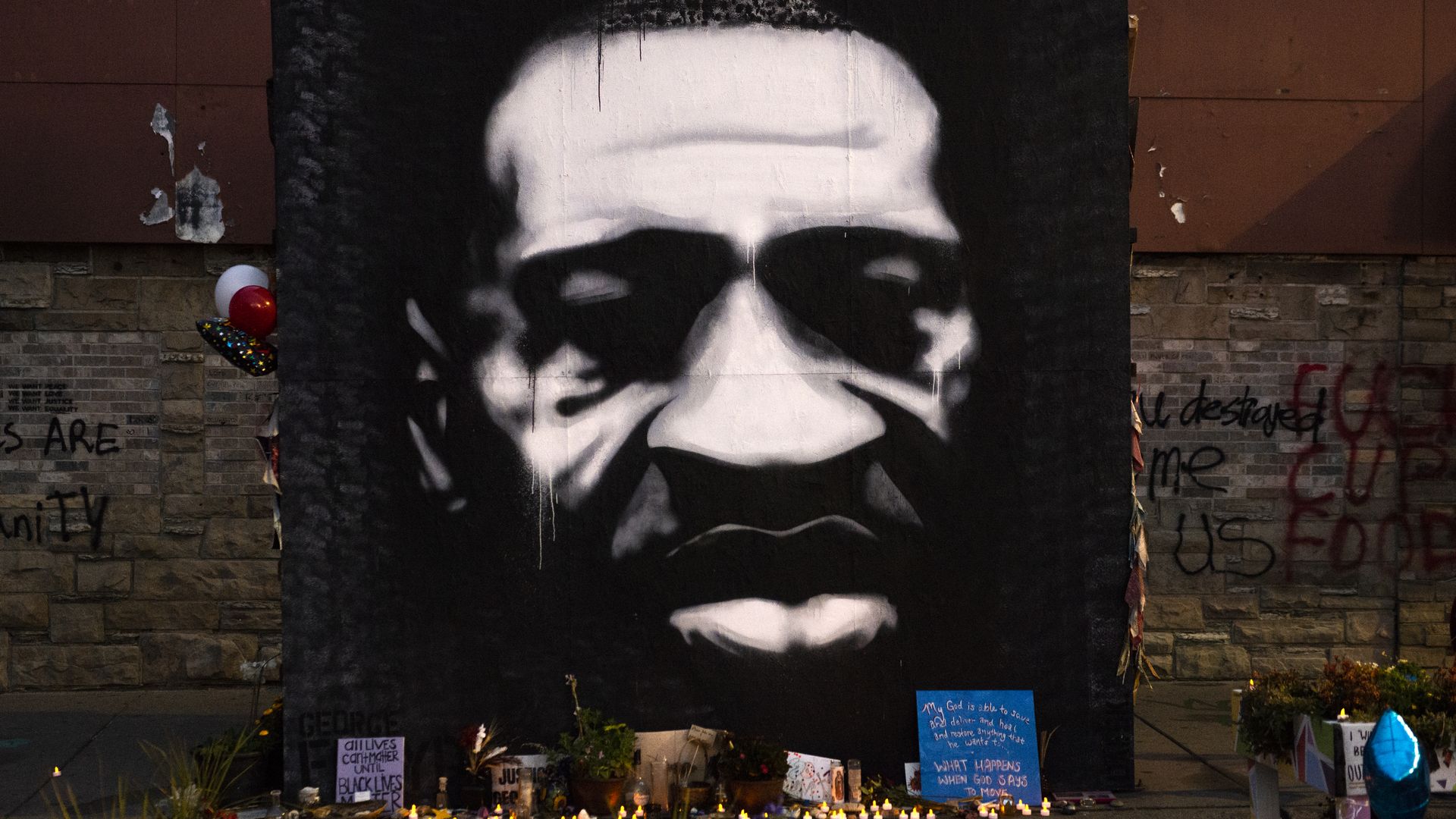 A mural of George Floyd surrounded by candles and flowers 