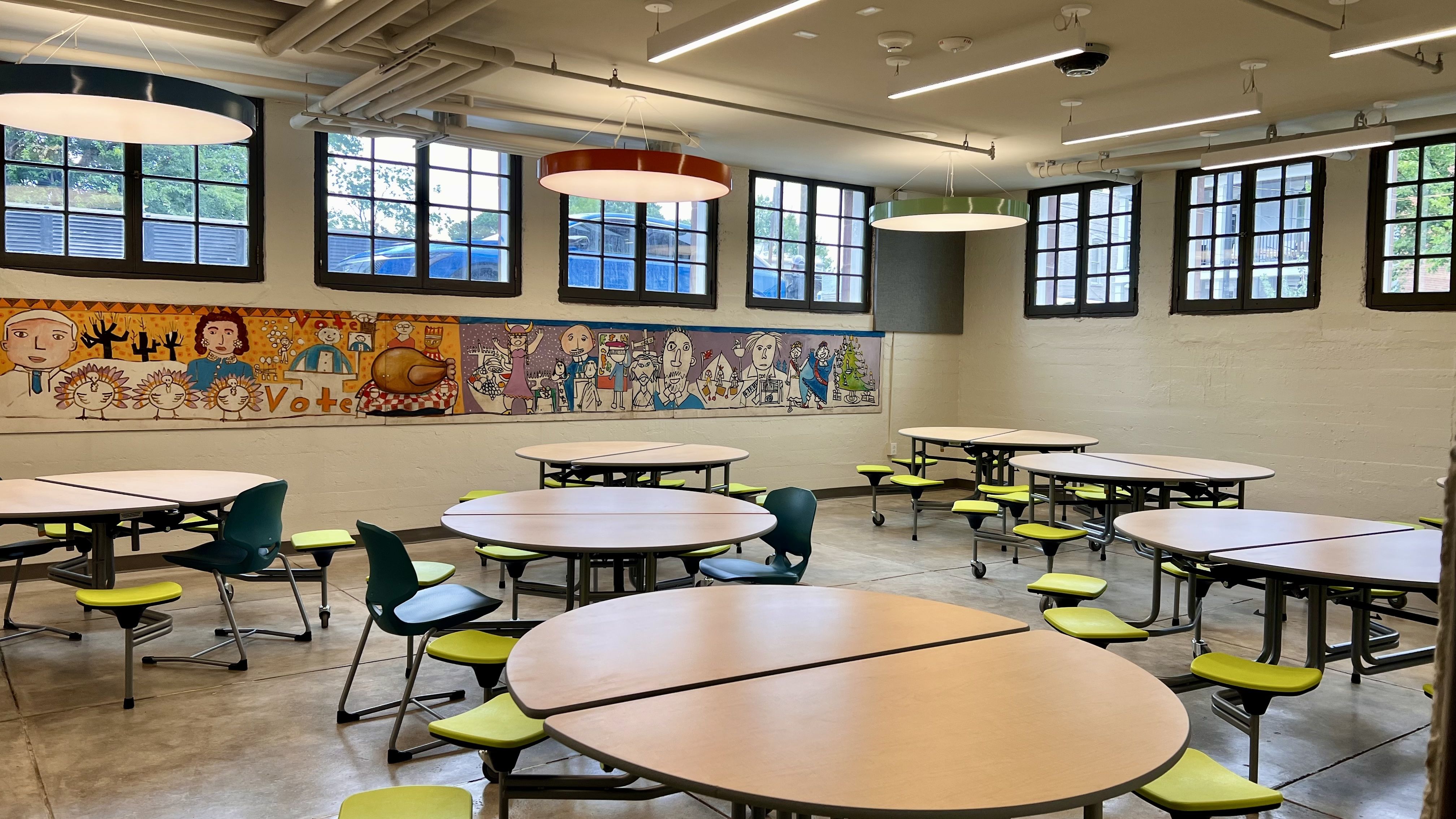 a lunchroom with round tables and bright colored chairs