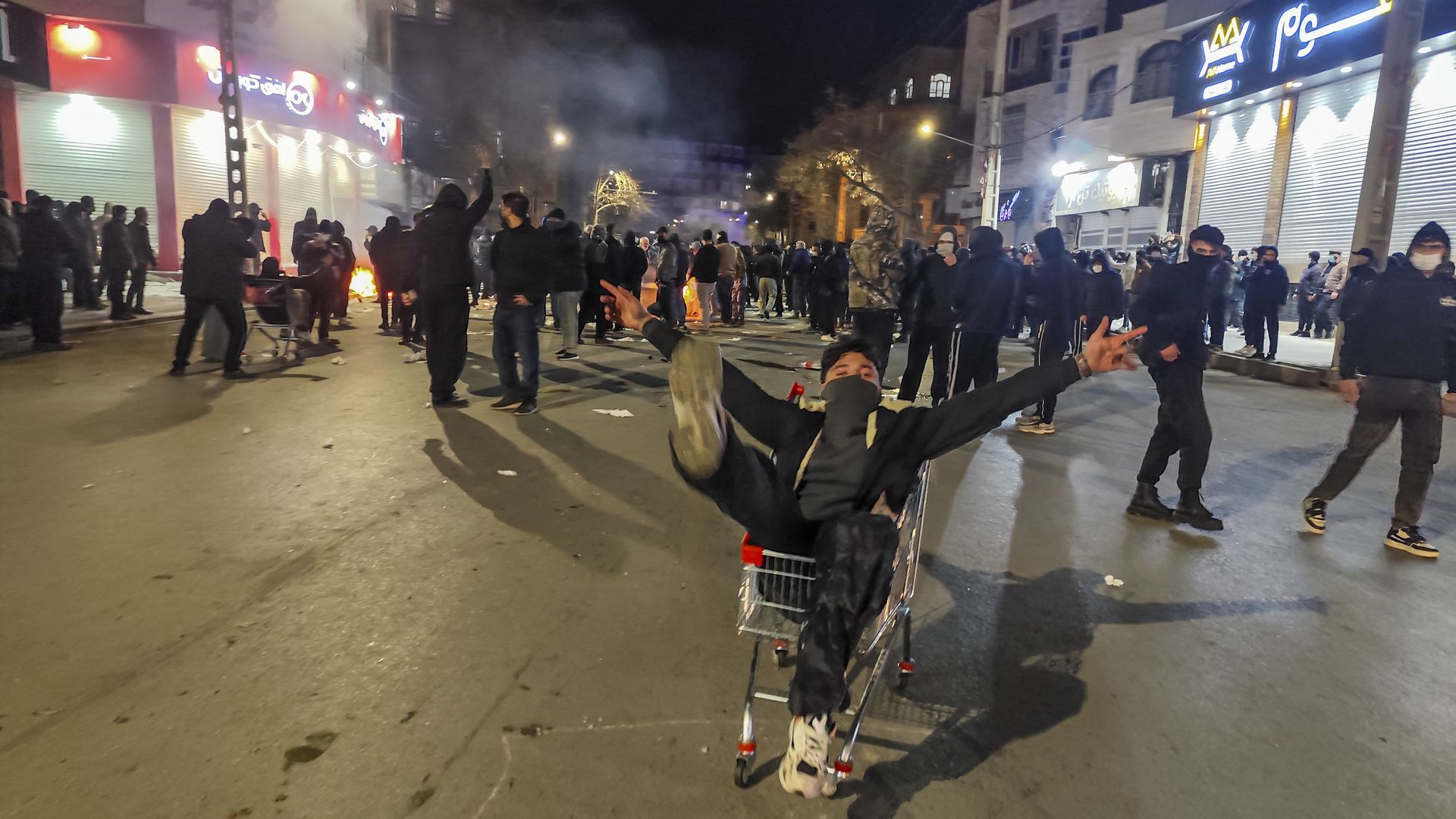 Man in shopping cart in busy street of protests