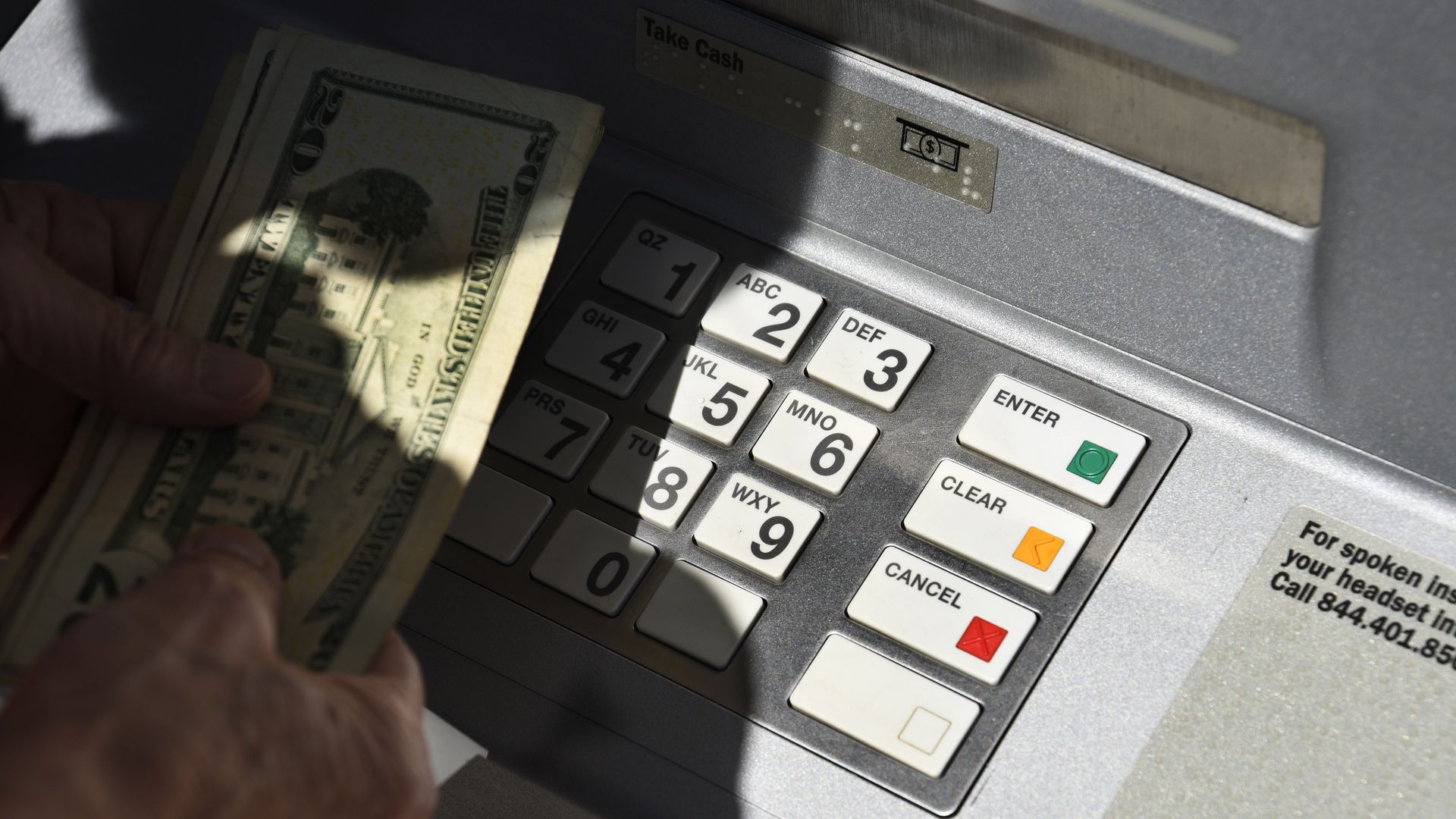Someone holding a handful of cash at an ATM
