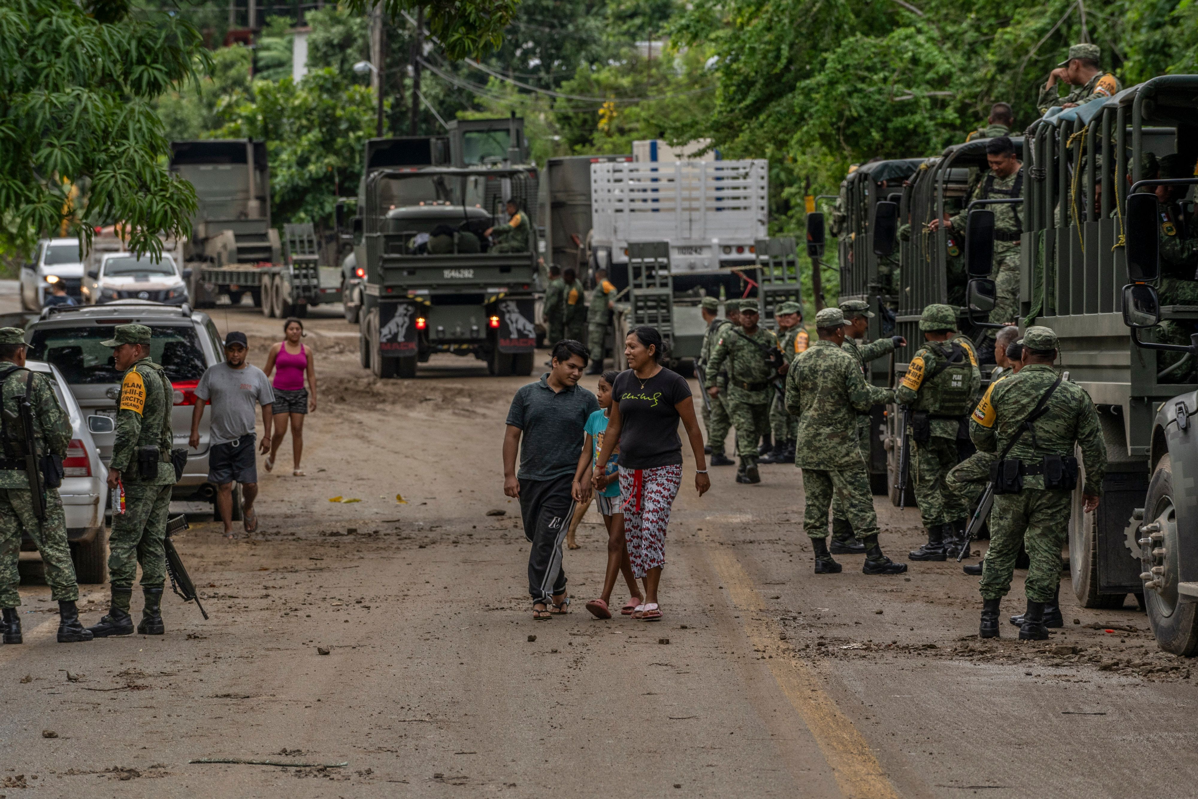 People and Mexican soldiers stranded on Oct. 25 as they wait for an engineer corps to fix a bridge damaged in the storm.
