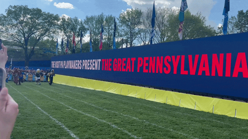 The Nittany Lion Mascot racing on green grass and beating three other Pennsylvania mascots