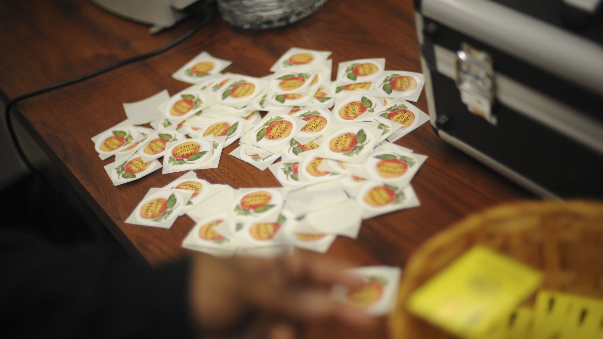 In this image, a pile of stickers with the text "Georgia voter" are shown on a table