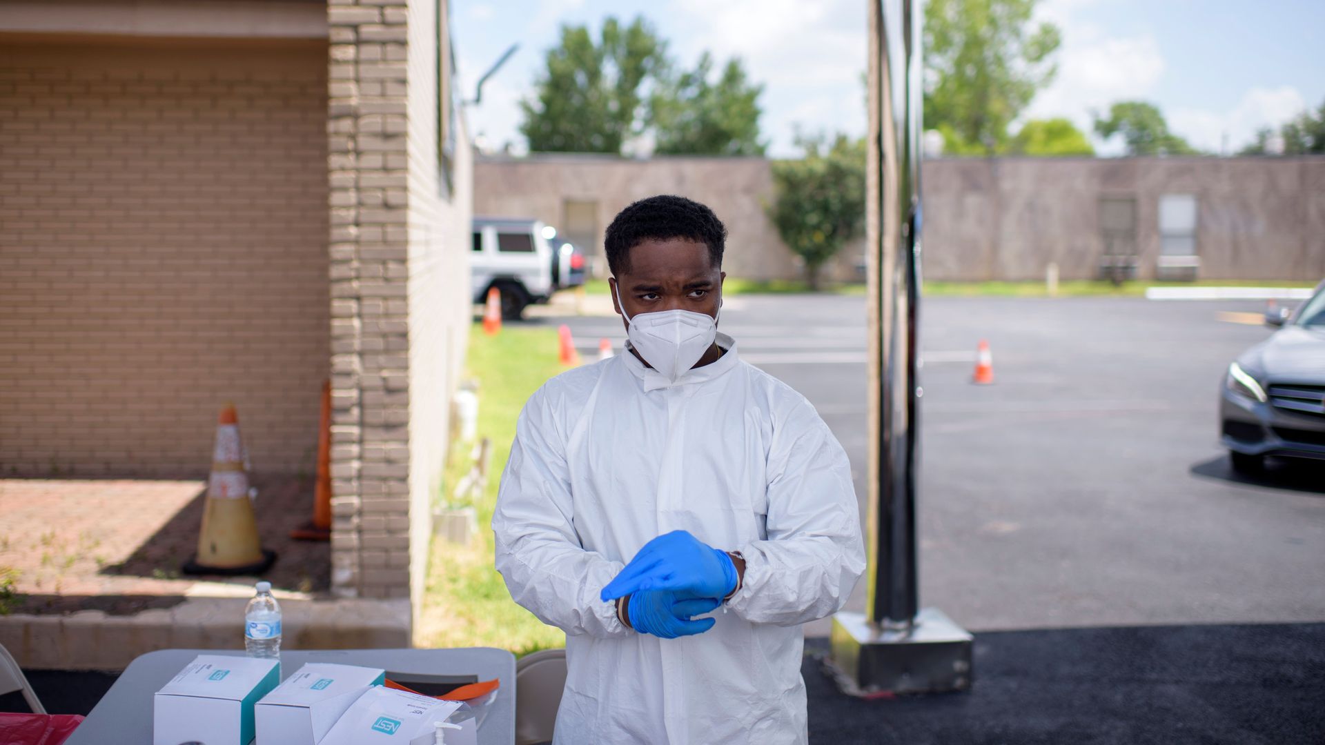 A healthcare worker wears personal protective equipment including a mask and gloves