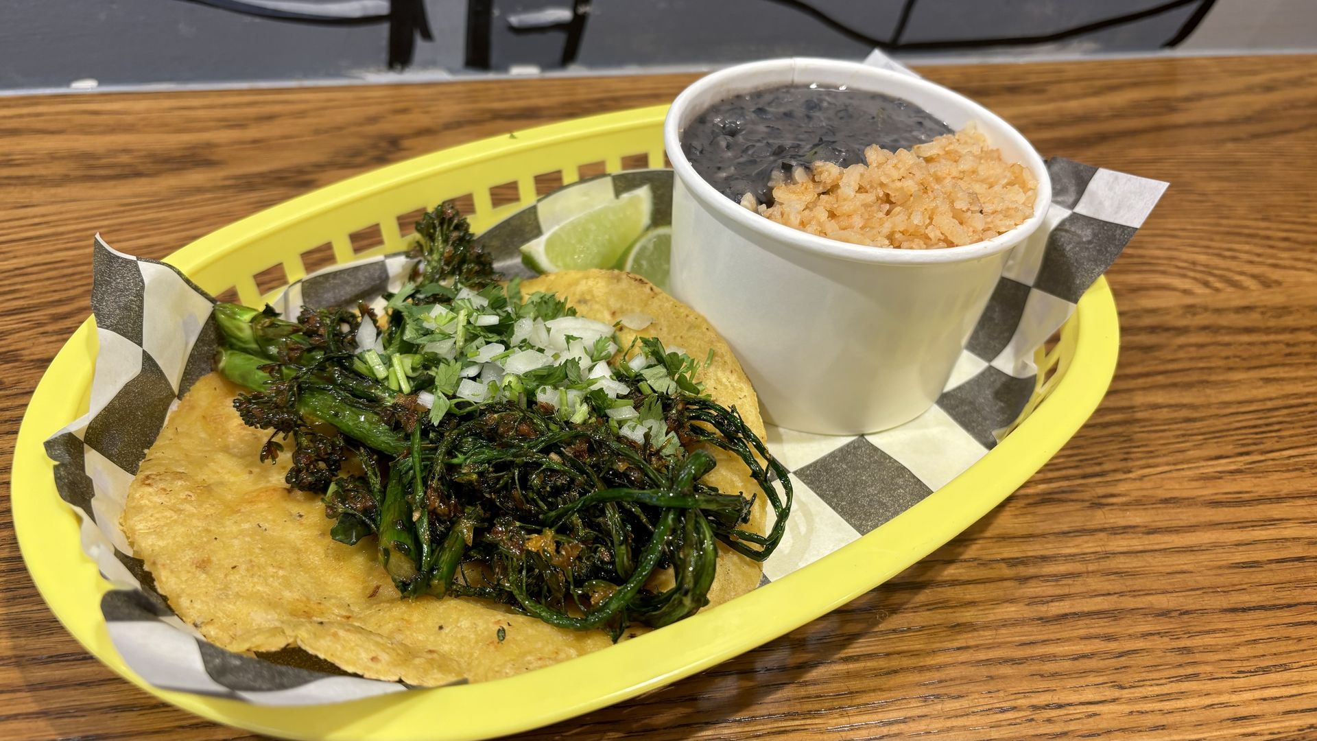 A taco with a cup of rice and beans in a basket