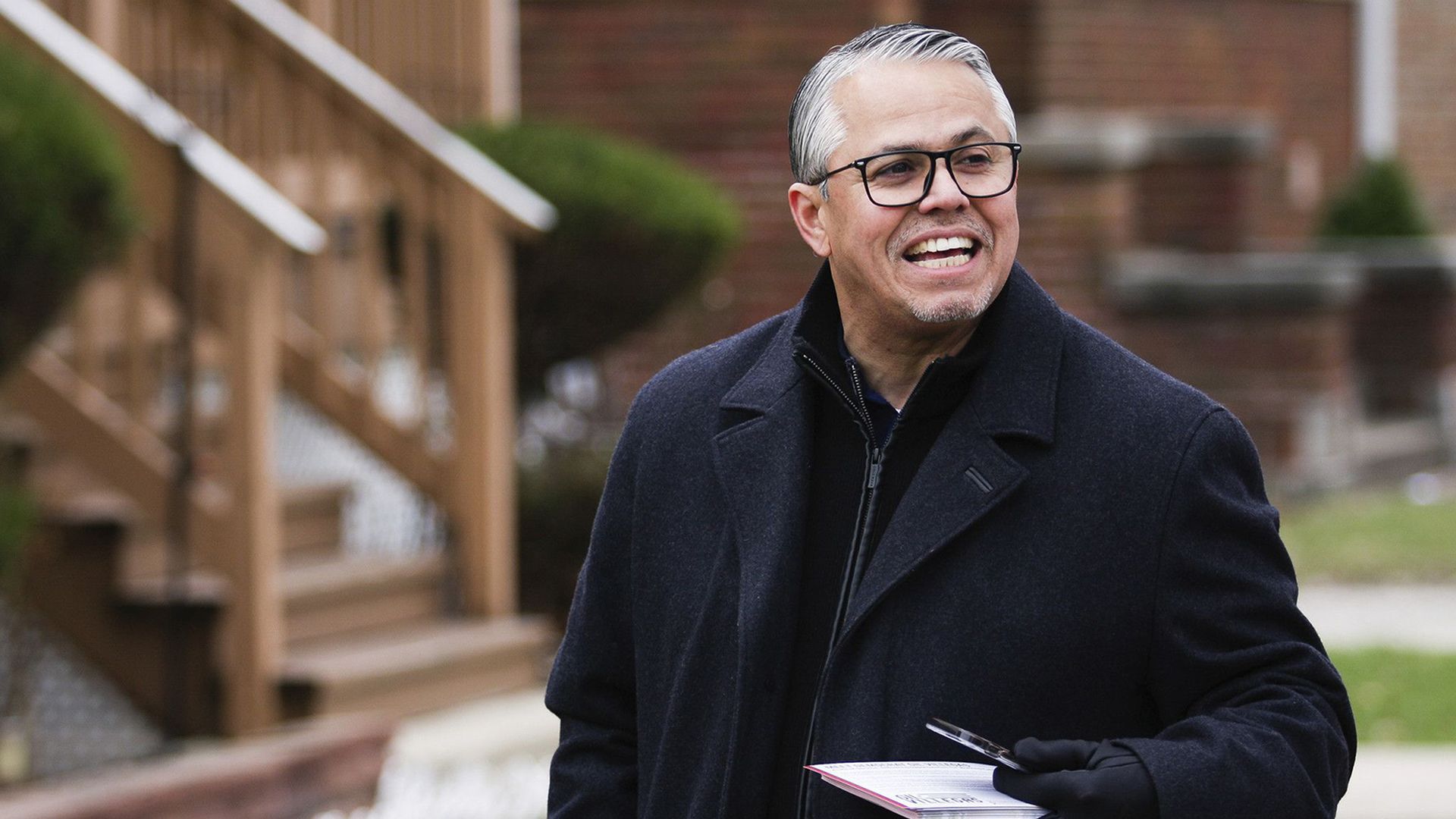 Photo of a man holding paper talking off camera. 