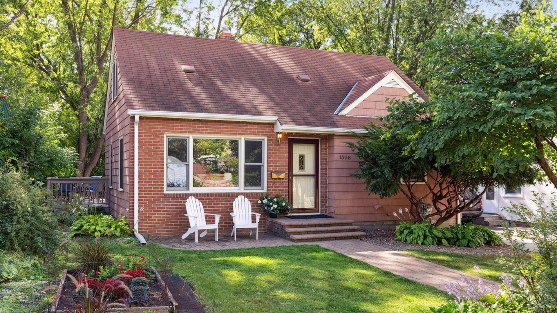 brick red home with porch with white chairs